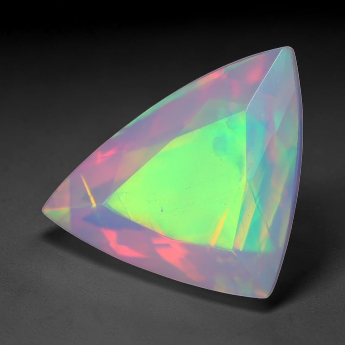 2.11ct Natural Ethiopian Welo Faceted Opal, 3EB: This expertly faceted finished opal holds soft shifting internal light phenomena visible across polished reflective planes within its 10.3x8.7x6.6mm calibrated measurements, precise faceting structure