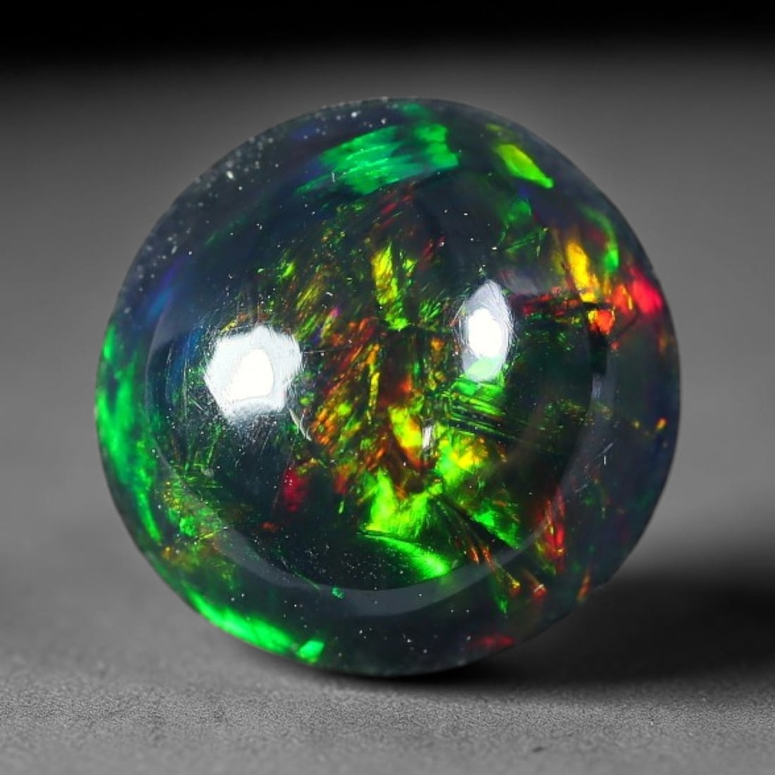 1.93ct Natural Ethiopian Welo Black Smoked Opal Cabochon Loose Gemstone, 76FX: This fully polished Ethiopian Welo opal features a dark smoked base with vivid, sweeping play-of-color shifting across its glossy dome surface, measured at 9x5mm. The black smoke treatment deepens the