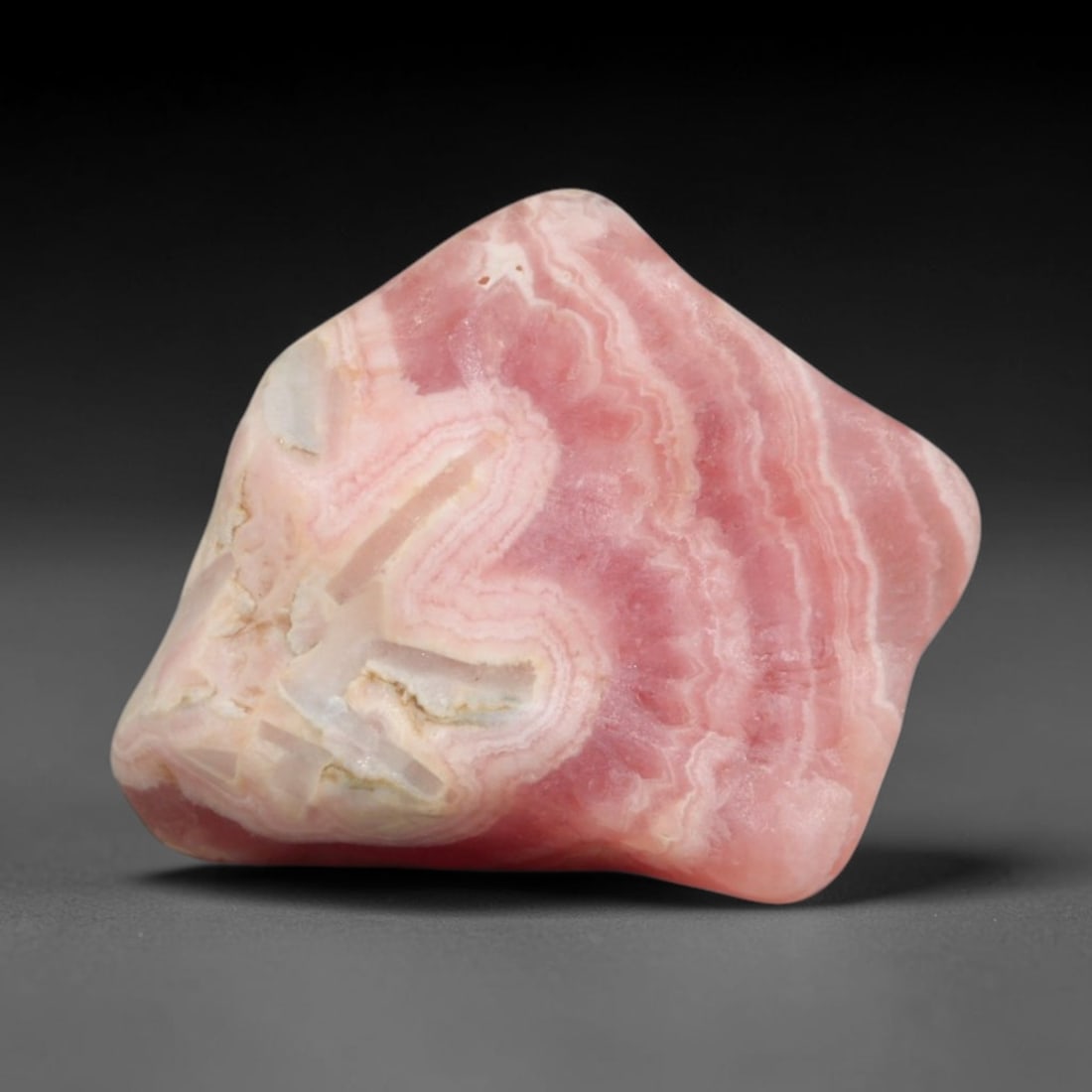 40ct Natural Argentine Rhodochrosite Tumbled Banded Rough Specimen, 100FC: This smooth rounded rough specimen is natural banded rhodochrosite sourced from Argentina's Capillitas mining district, displaying characteristic layered concentric banding of soft blush pink, creamy 