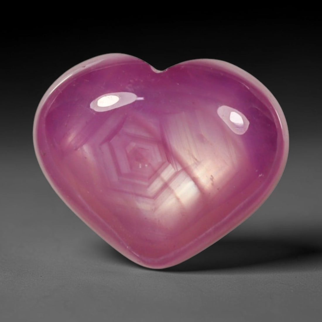 4.94ct Natural Mozambique Hot Pink Ruby Loose Gemstone, 81BP: This heart shaped Mozambique ruby cabochon measures 1mm, showcasing a vivid saturated hot pink body paired with stunning natural hexagonal crystal growth banding that forms a distinct geometric layere