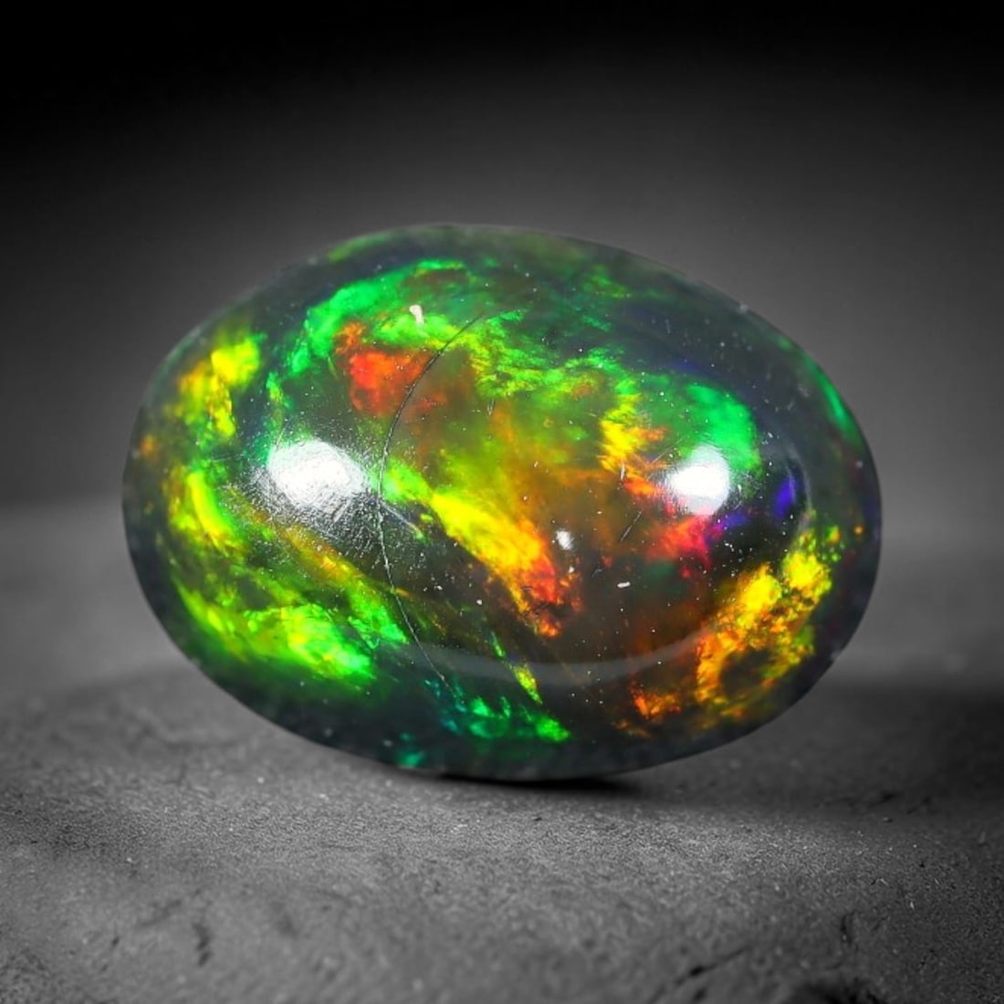 2.30ct Natural Ethiopian Welo Black Smoked Opal Cabochon Loose Gemstone, 38FX: This fully polished Ethiopian Welo opal features a dark smoked base with vivid, sweeping play-of-color shifting across its glossy dome surface, measured at 10x7x5mm. The black smoke treatment deepens 