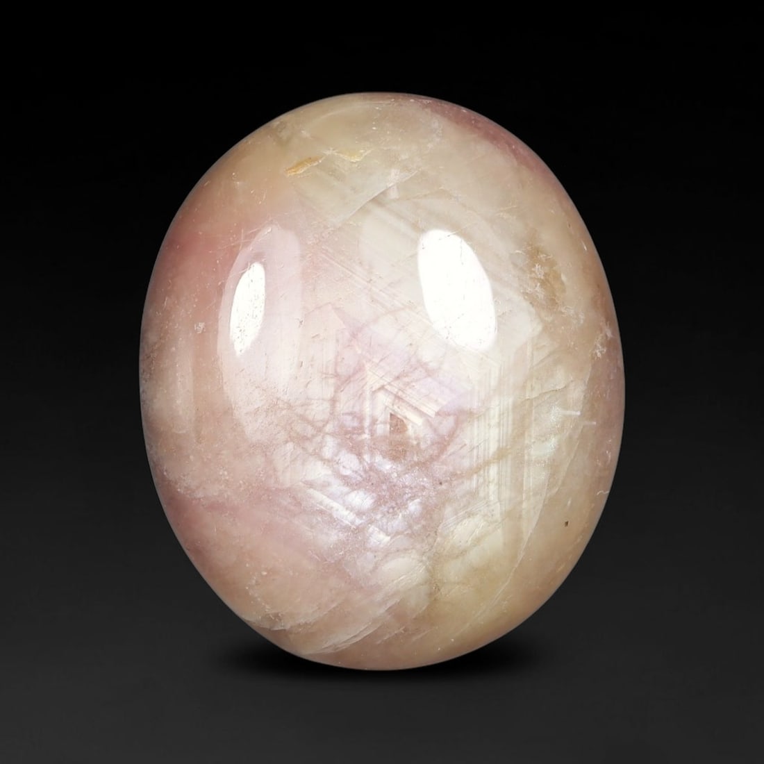 22.72 Carats Natural Madagascar Soft Rose Pink Heated Ruby Cabochon Loose Gemstone, 50FE: This warm blush-toned ruby cabochon carries blended swathes of soft rose pink and gentle peach undertones, with faint natural mineral veining throughout the polished dome, measured at 17.6x14.9x7.5mm.