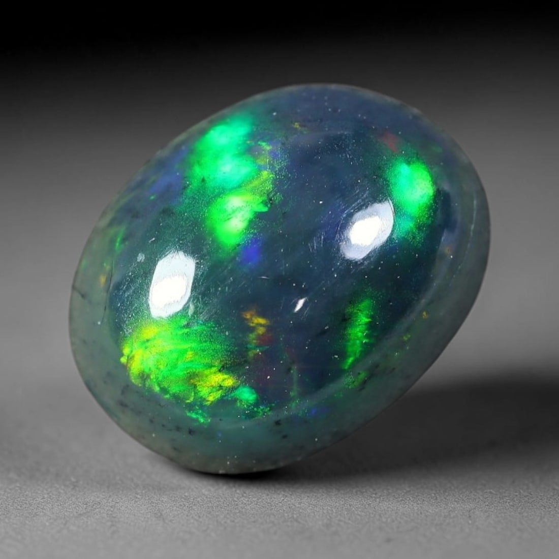 2.13ct Natural Ethiopian Welo Black Smoked Opal Cabochon Loose Gemstone, 57FX: This fully polished Ethiopian Welo opal features a dark smoked base with vivid, sweeping play-of-color shifting across its glossy dome surface, measured at 11x8x5mm. The black smoke treatment deepens 