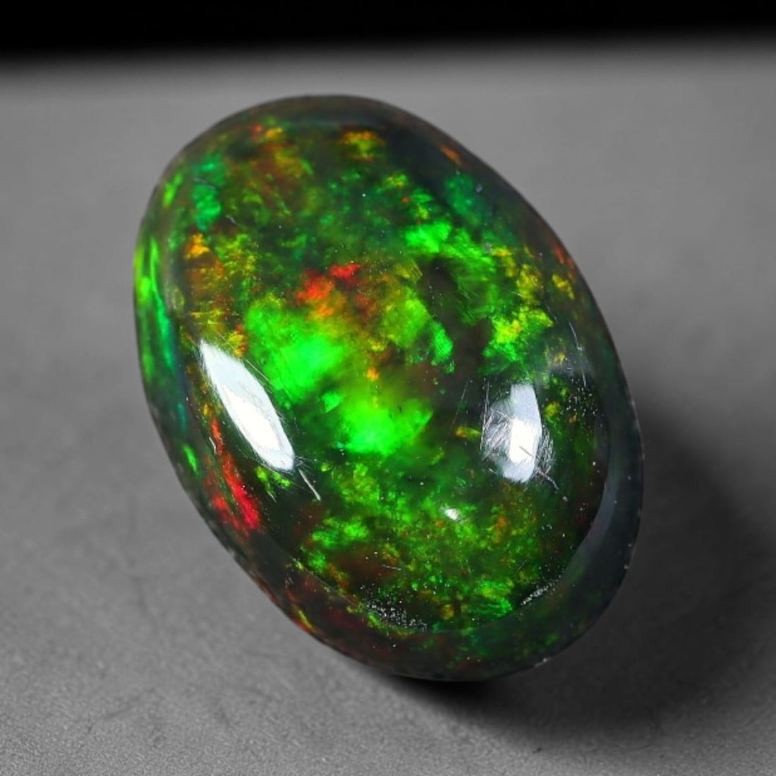 1.96ct Natural Ethiopian Welo Black Smoked Opal Cabochon Loose Gemstone, 53FX: This fully polished Ethiopian Welo opal features a dark smoked base with vivid, sweeping play-of-color shifting across its glossy dome surface, measured at 10x8x4mm. The black smoke treatment deepens 