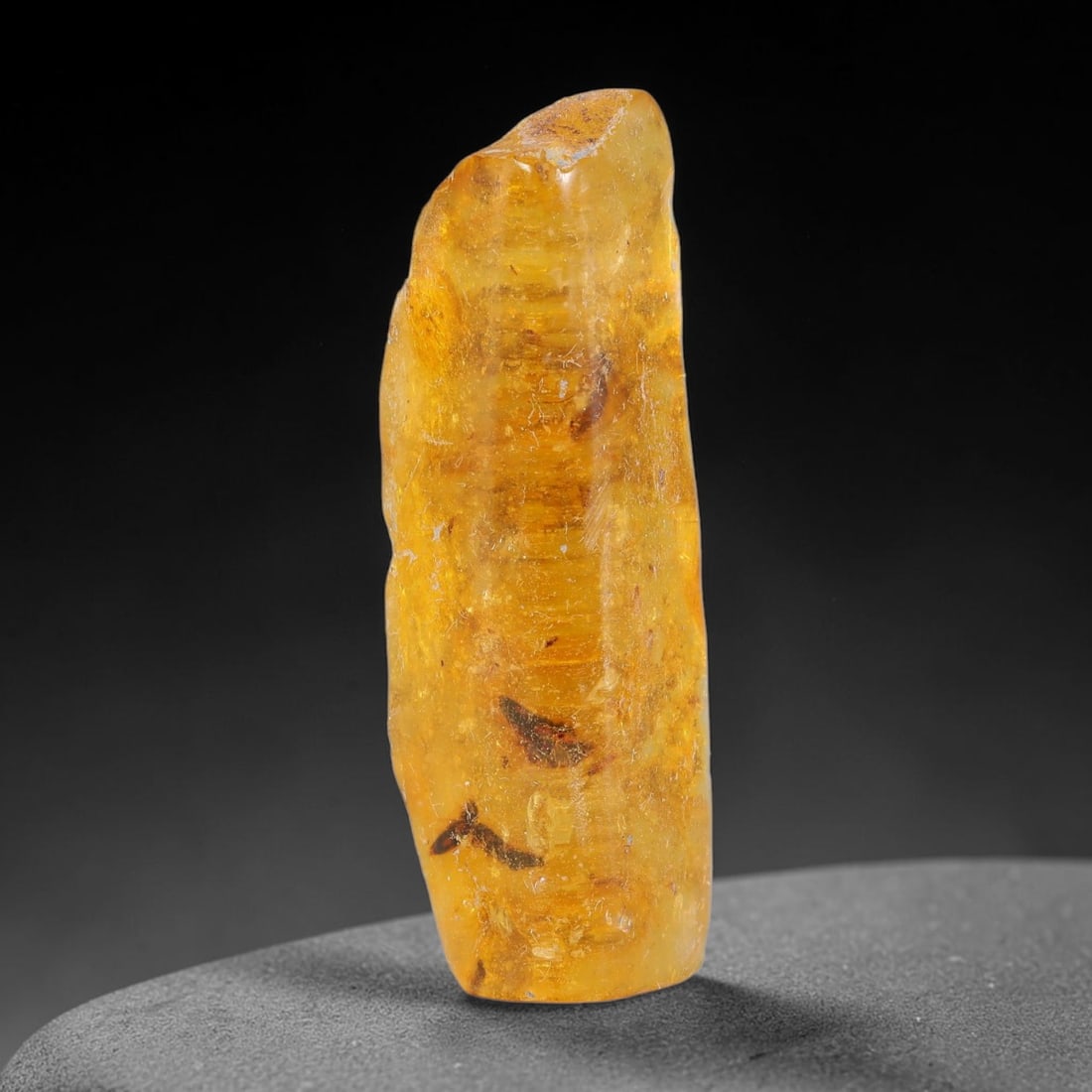 12.97ct Natural Baltic Polished Loose Freeform Amber Gemstone, 69FL: This smoothly polished freeform amber piece carries warm translucent organic clarity with fine natural fossil flecks and tiny mineral inclusions suspended throughout its 38x13x8mm flowing unstructured