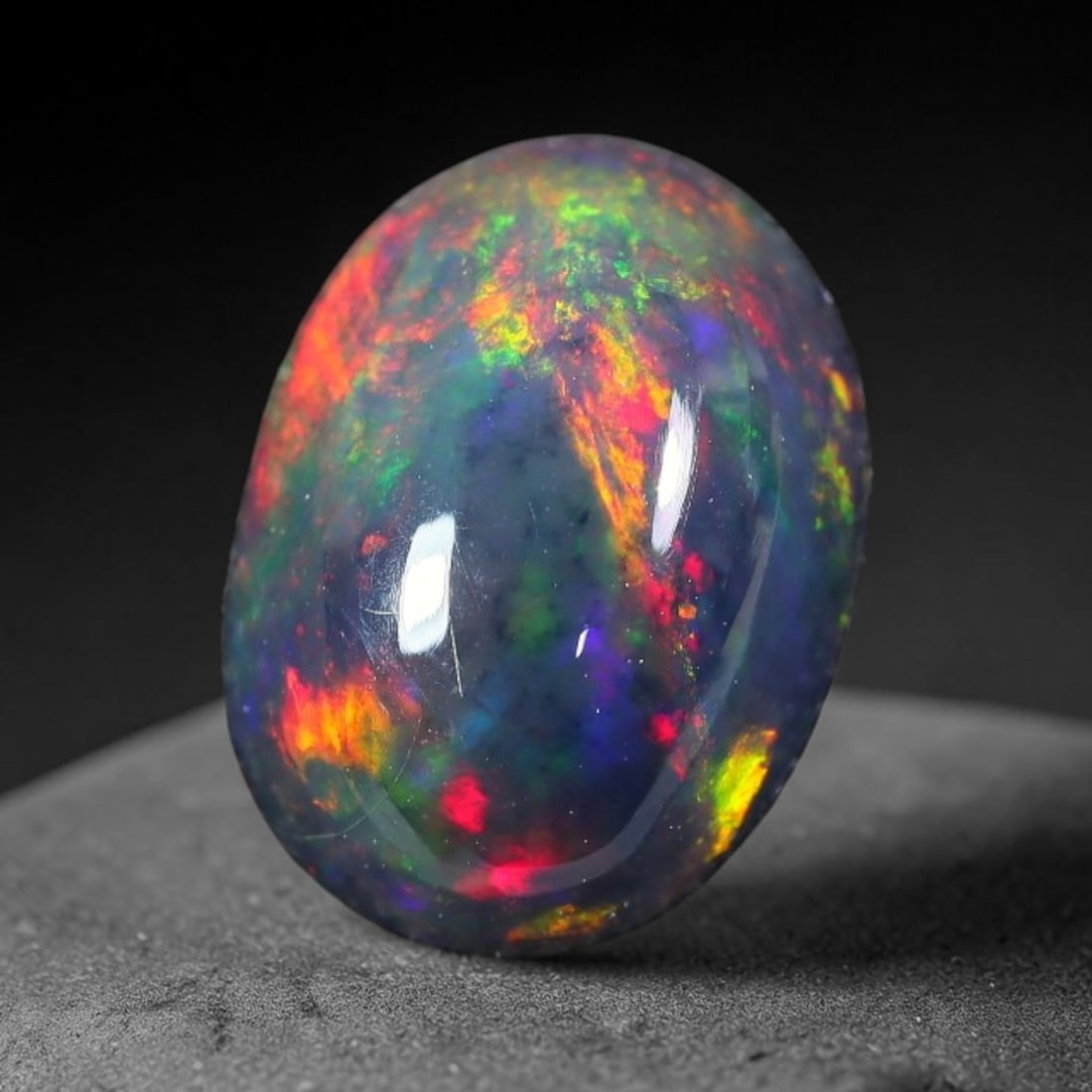 1.64ct Natural Ethiopian Welo Black Smoked Opal Cabochon Loose Gemstone, 16FX: This fully polished Ethiopian Welo opal features a dark smoked base with vivid, sweeping play-of-color shifting across its glossy dome surface, measured at 10x7x4mm. The black smoke treatment deepens 