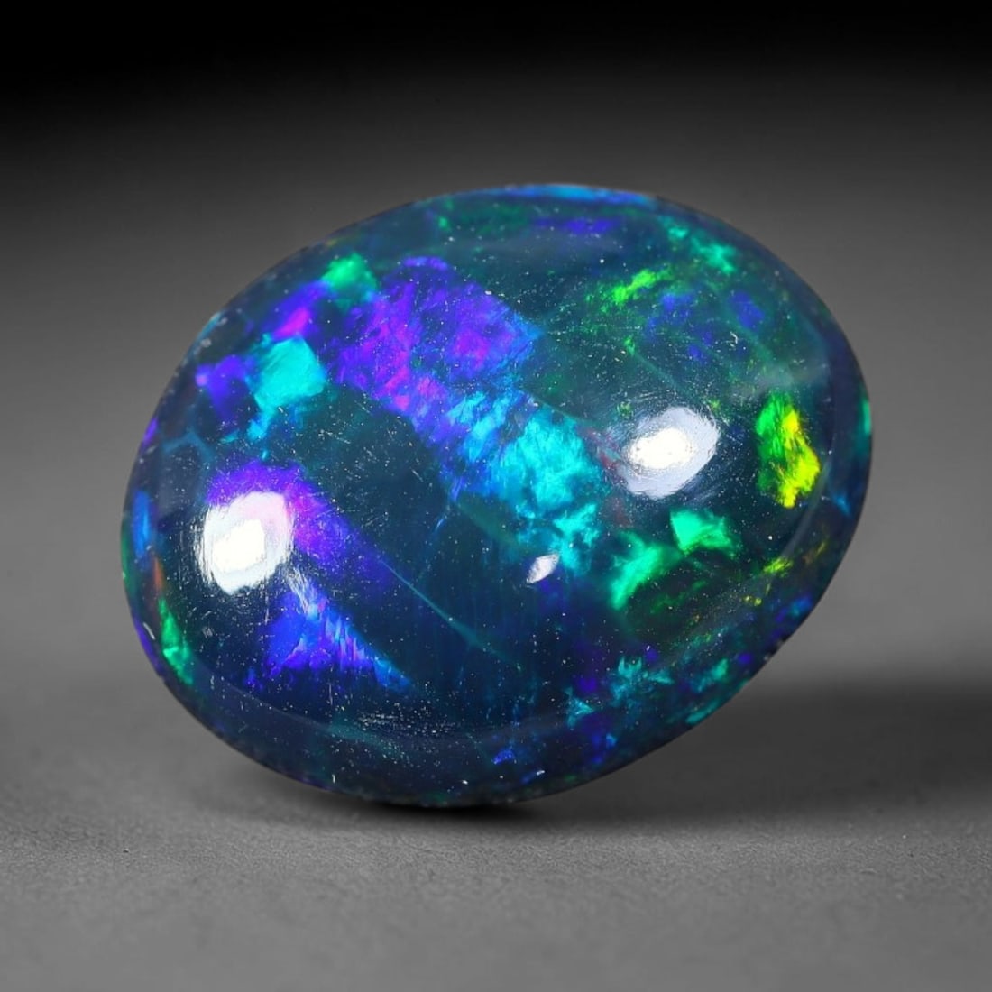 2.27ct Natural Ethiopian Welo Black Smoked Opal Cabochon Loose Gemstone, 55FX: This fully polished Ethiopian Welo opal features a dark smoked base with vivid, sweeping play-of-color shifting across its glossy dome surface, measured at 12x9x4mm. The black smoke treatment deepens 