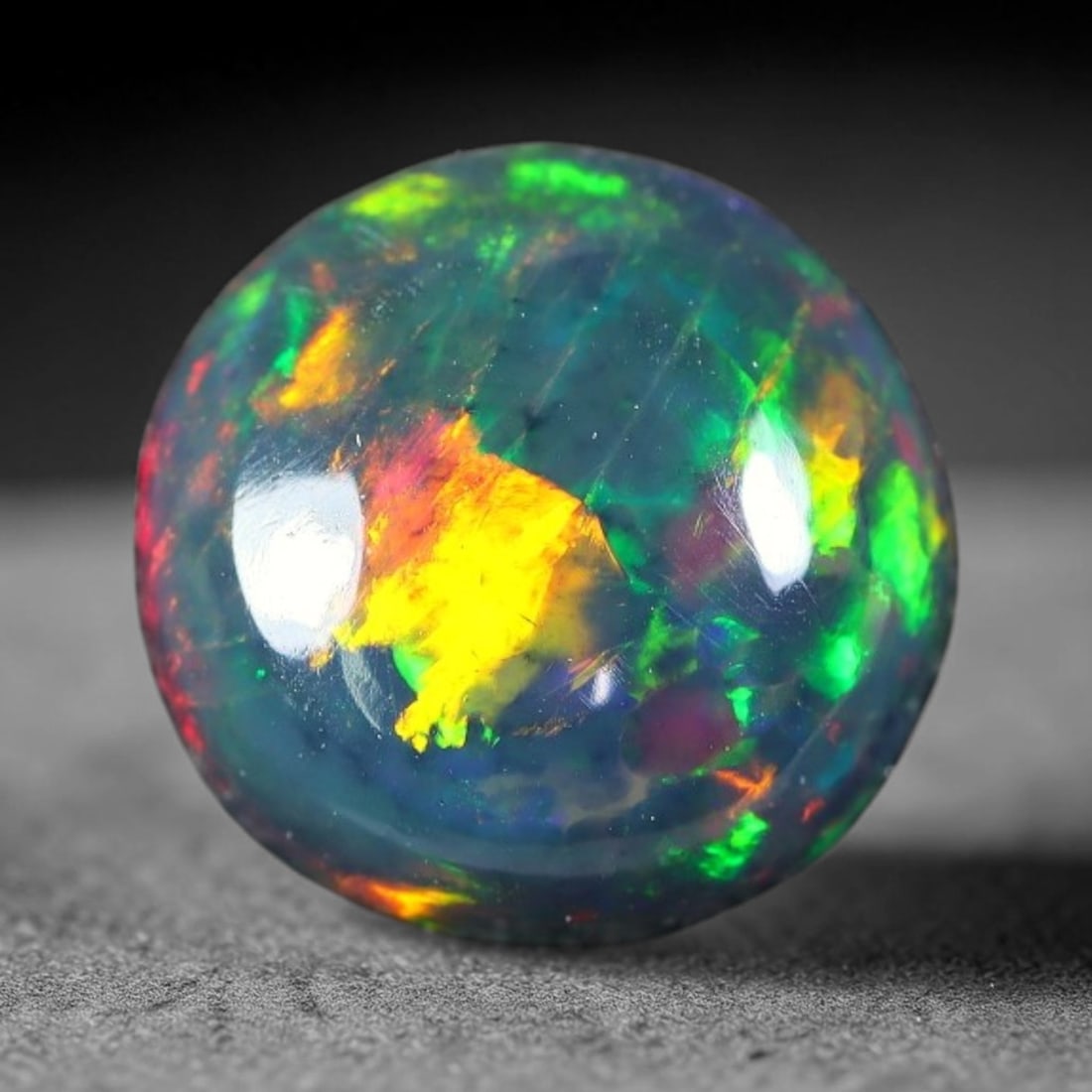 1.94ct Natural Ethiopian Welo Black Smoked Opal Cabochon Loose Gemstone, 35FX: This fully polished Ethiopian Welo opal features a dark smoked base with vivid, sweeping play-of-color shifting across its glossy dome surface, measured at 9x4mm. The black smoke treatment deepens the