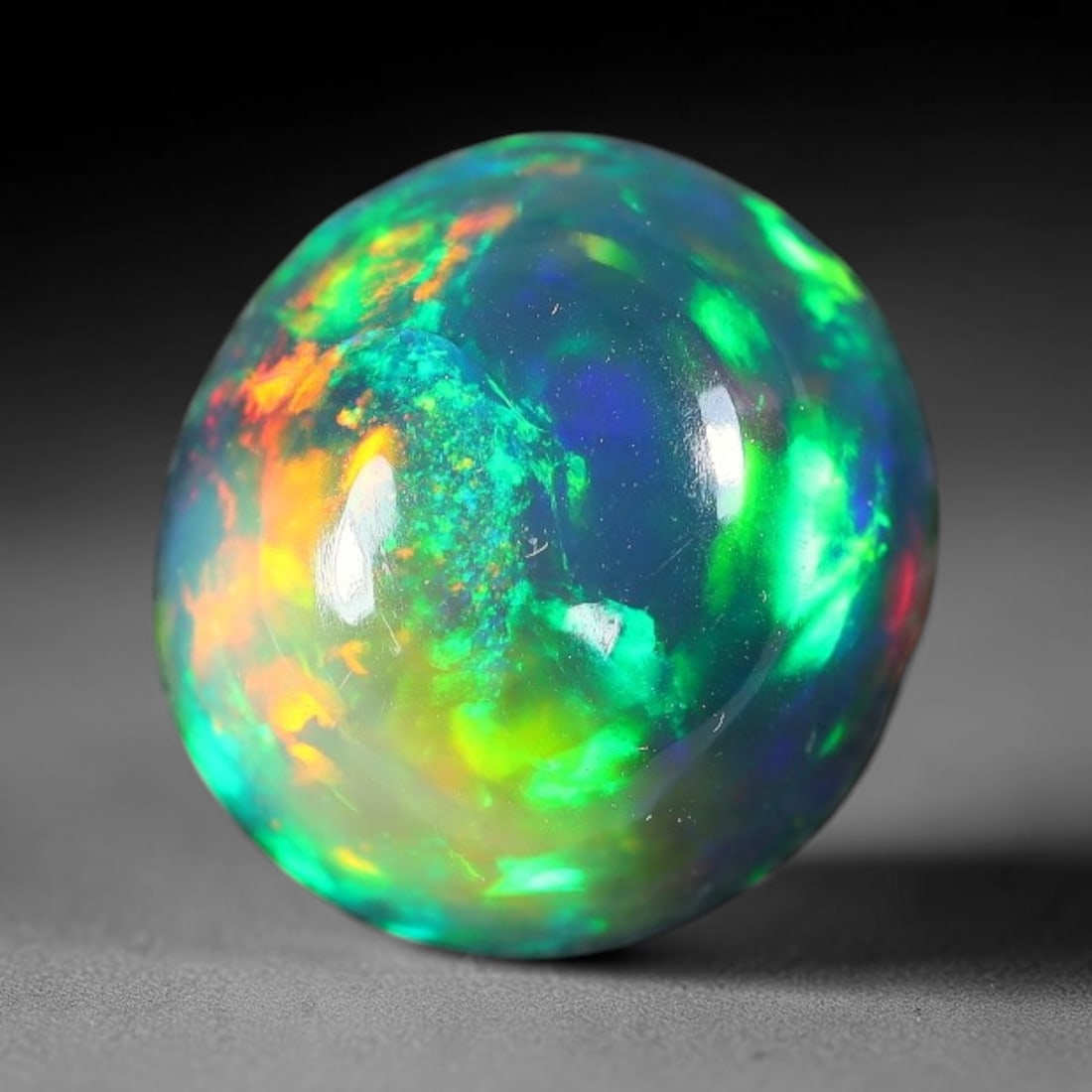 3.29ct Natural Ethiopian Welo Black Smoked Opal Cabochon Loose Gemstone, 26FX: This fully polished Ethiopian Welo opal features a dark smoked base with vivid, sweeping play-of-color shifting across its glossy dome surface, measured at 9x7mm. The black smoke treatment deepens the