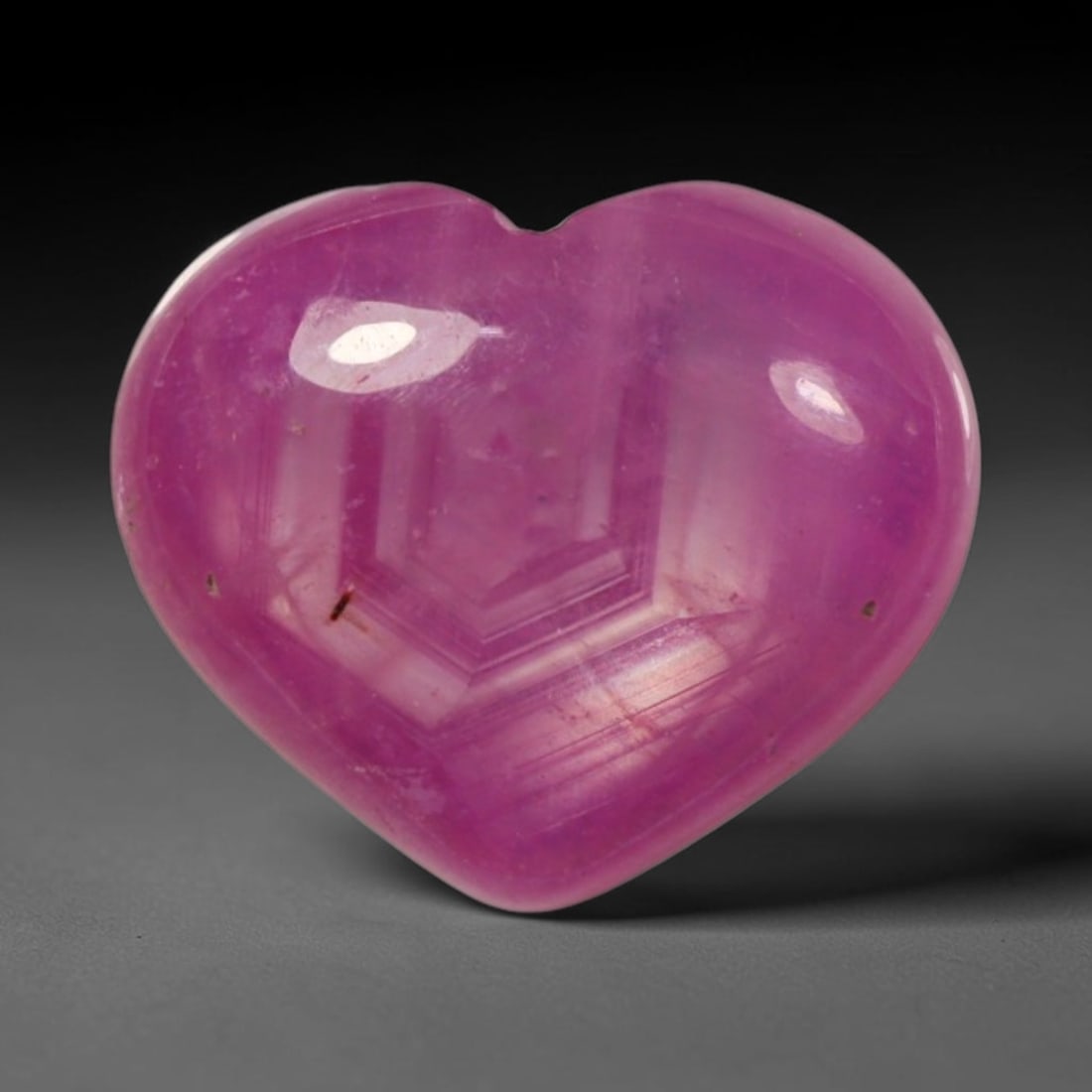 4.57ct Natural Mozambique Hot Pink Ruby Loose Gemstone, 64BP: This heart shaped Mozambique ruby cabochon measures 11.1x9.5x4.2mm, showcasing a vivid saturated hot pink body paired with stunning natural hexagonal crystal growth banding that forms a distinct geome