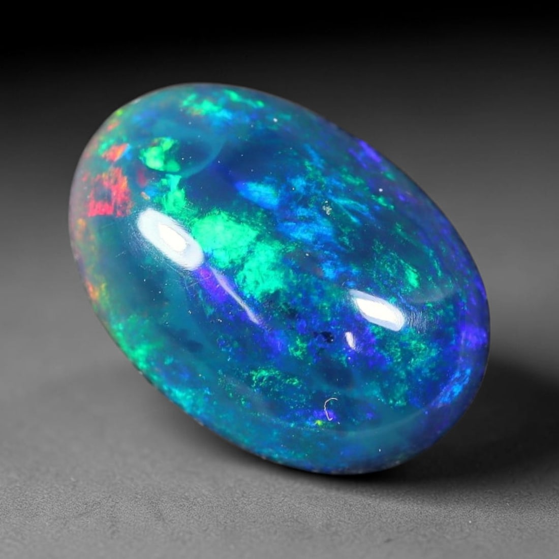 1.63ct Natural Ethiopian Welo Black Smoked Opal Cabochon Loose Gemstone, 52FX: This fully polished Ethiopian Welo opal features a dark smoked base with vivid, sweeping play-of-color shifting across its glossy dome surface, measured at 11x8x4mm. The black smoke treatment deepens 