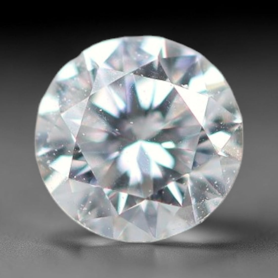 0.12ct Lab-Grown White Round Brilliant HPHT Diamond Loose Gemstone, 76BE: This precision-cut HPHT lab-grown diamond exhibits brilliant colourless transparency, dotted with subtle microscopic growth features within its crystal structure, measured at calibrated dimensions of 