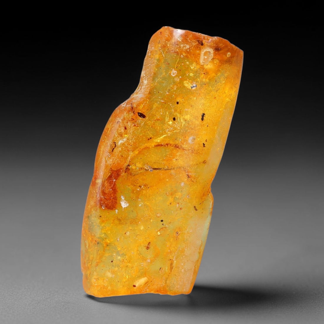16.16ct Natural Baltic Polished Loose Freeform Amber Rough, 24EK: This smoothly polished freeform amber piece carries warm translucent organic clarity with fine natural fossil flecks and tiny mineral inclusions suspended throughout its 38x17x10mm flowing unstructure