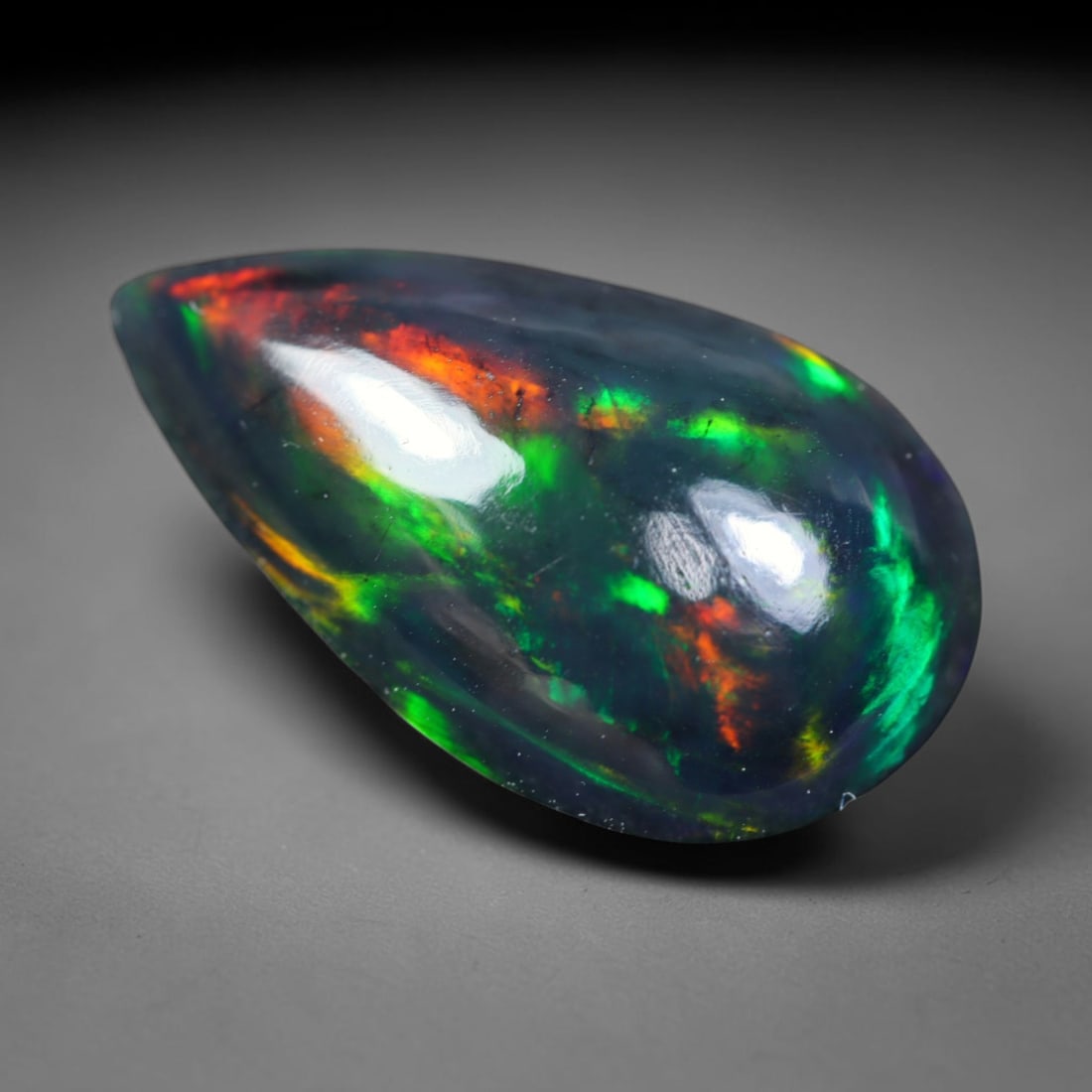 2.55ct Natural Ethiopian Welo Black Smoked Opal Cabochon Loose Gemstone, 45FL: This fully polished Ethiopian Welo opal features a dark smoked base with vivid, sweeping play-of-color shifting across its glossy dome surface, measured at 15x9.1x4.6mm. The black smoke treatment deep