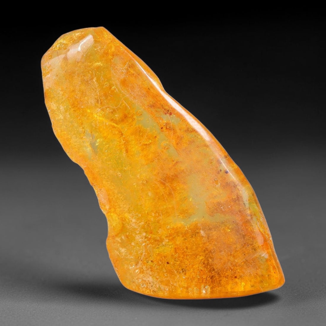 16ct Natural Baltic Polished Loose Freeform Amber Gemstone, 57EB: This smoothly polished freeform amber piece carries warm translucent organic clarity with fine natural fossil flecks and tiny mineral inclusions suspended throughout its 39x20mm flowing unstructured s