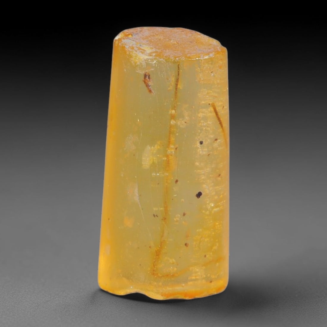 9.25ct Natural Baltic Polished Loose Freeform Amber Gemstone, 21AT: This smoothly polished freeform amber piece carries warm translucent organic clarity with fine natural fossil flecks and tiny mineral inclusions suspended throughout its 23x11mm flowing unstructured s