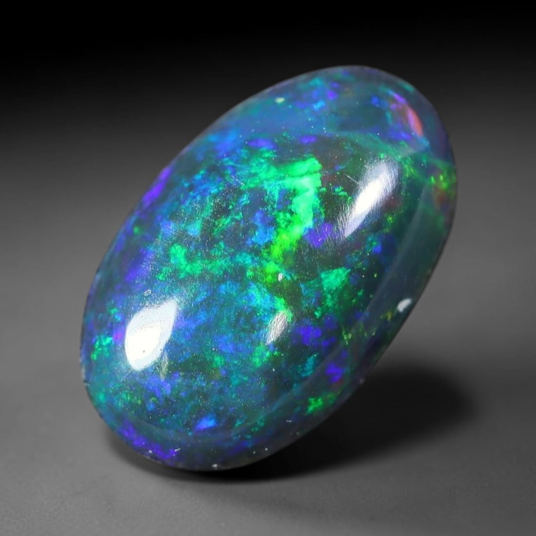 1.76ct Natural Ethiopian Welo Black Smoked Opal Cabochon Loose Gemstone, 61FX: This fully polished Ethiopian Welo opal features a dark smoked base with vivid, sweeping play-of-color shifting across its glossy dome surface, measured at 11x7x4mm. The black smoke treatment deepens 