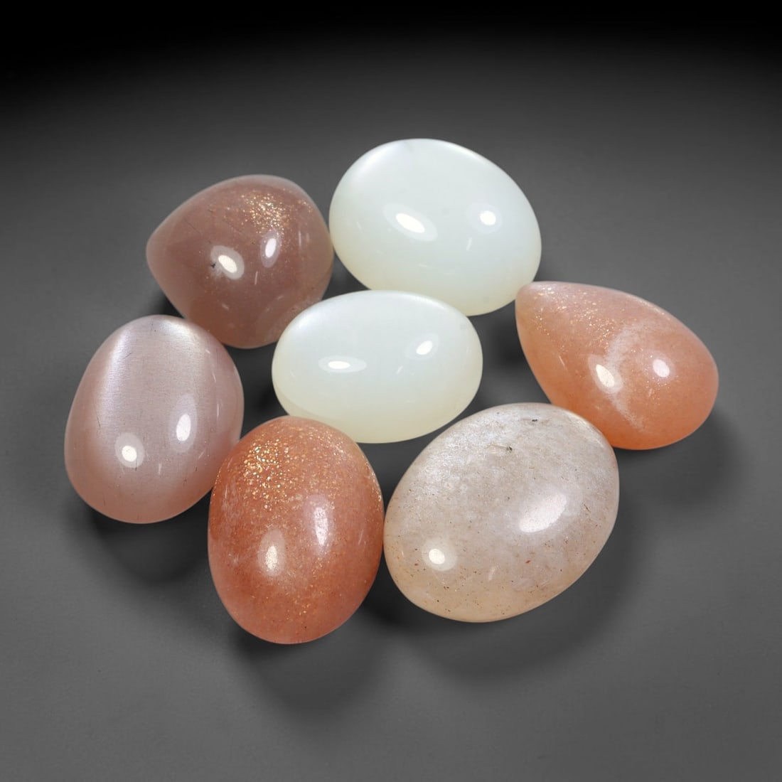 79.89ct Natural Ceylon Moonstone Cabochon Loose Gemstone Parcel Lot, 93EV: This substantial parcel of Ceylon moonstone cabochons showcases soft milky white, warm peach-pink and cool grey-silver tones across smoothly polished oval domed forms. Gentle adularescent sheen drifts