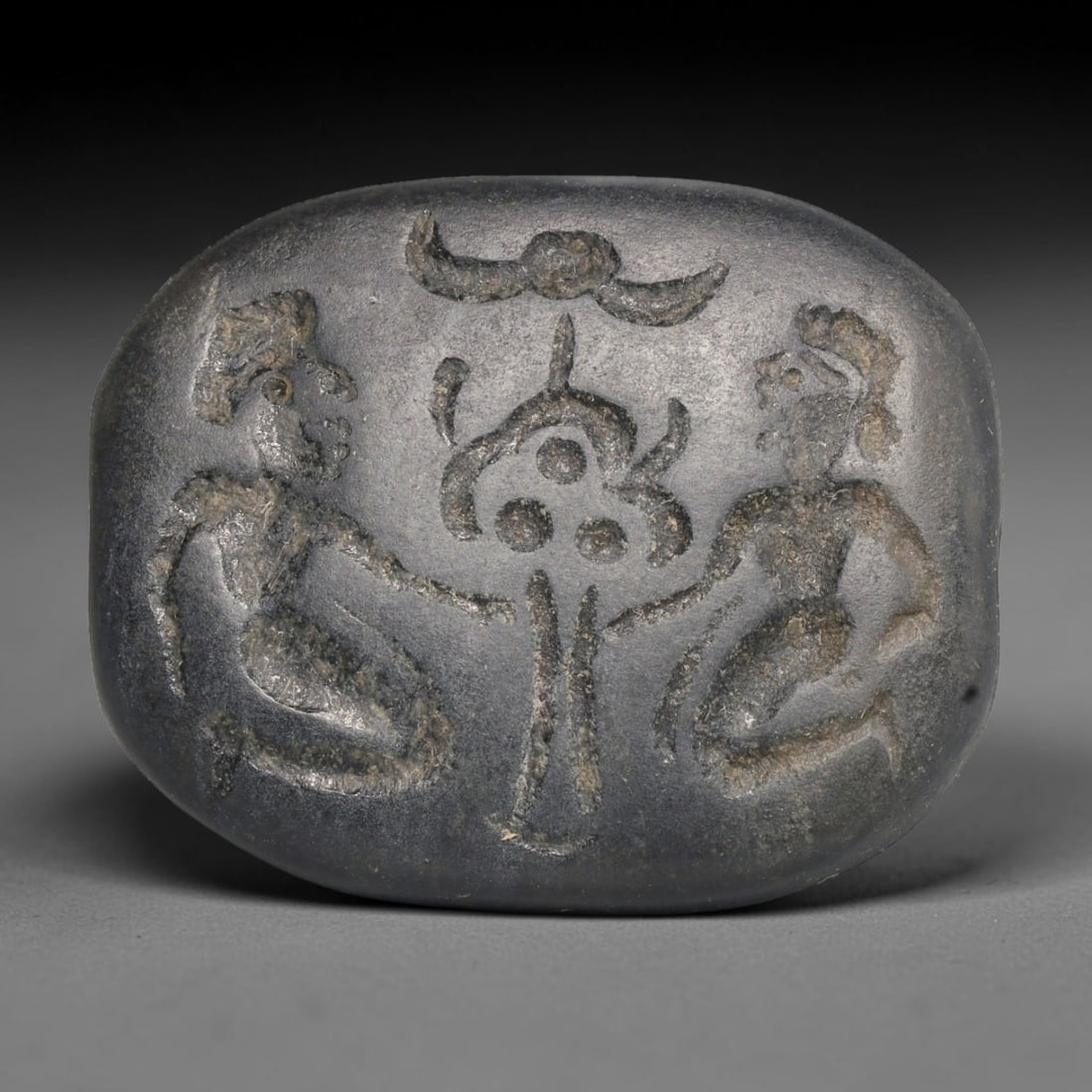 Ancient Sasanian Persian Intaglio Seal Bead (224-651 CE), 92EC: This antique dark stone oval intaglio seal bead originates from the Sasanian Persian Empire, renowned for sophisticated glyptic art used on talismanic seal amulets throughout late antiquity. The face 