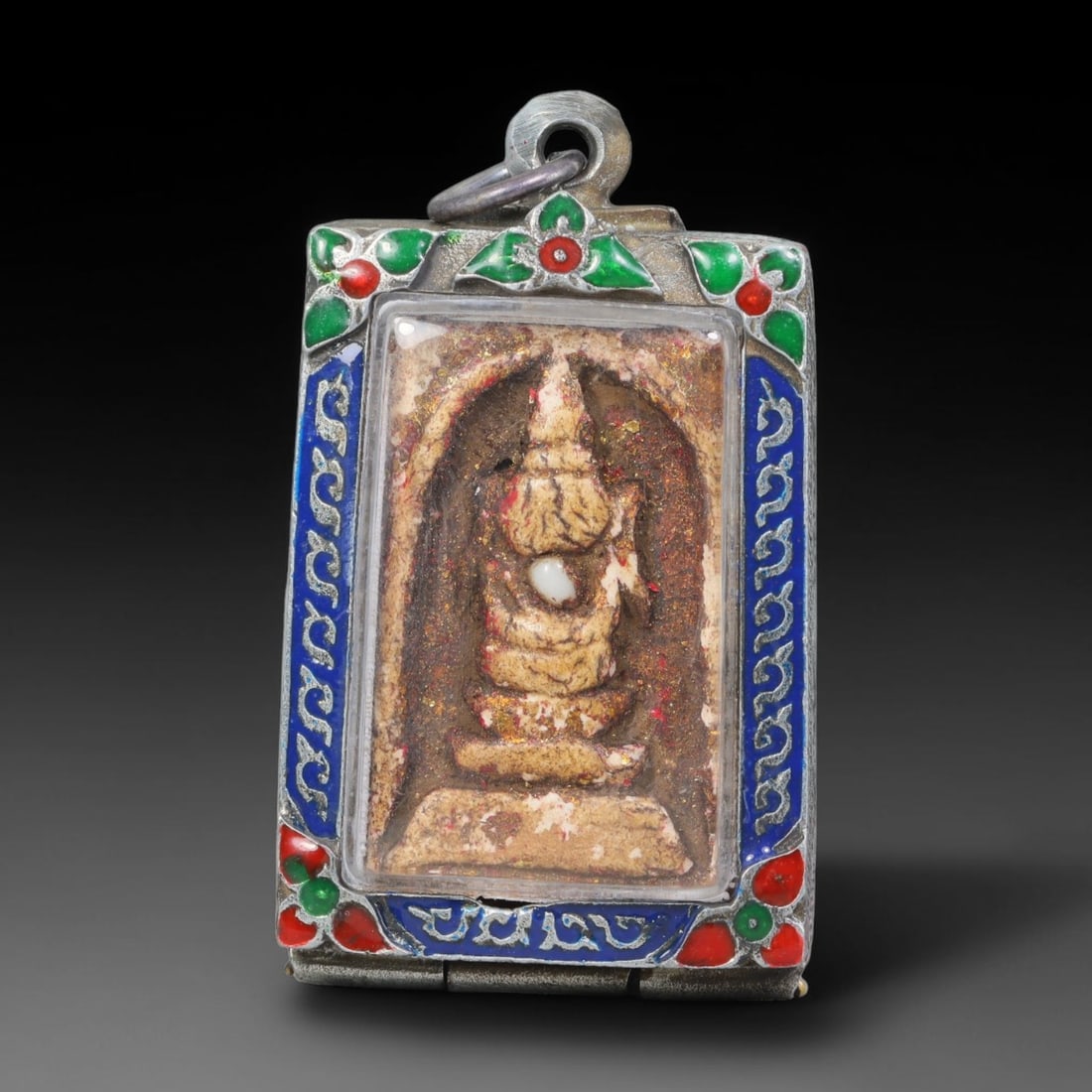 Thai Buddhist Folk Tradition Enclosed Amulet Pendant with Decorative Metal Casing, 14AH: This Thai sacred amulet is housed within an ornate hinged metal protective casing fitted with a top loop for wear as a pendant. The casing features intricate embossed surface detailing and a continuou