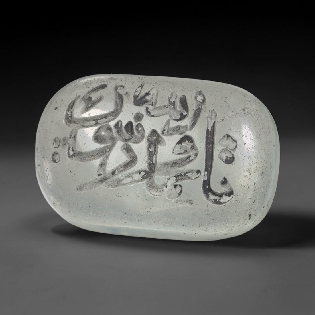 Early Vintage Islamic White Glass Calligraphic Script Intaglio Seal Cabochon (Post 1900 CE), 76BX: This early vintage glass intaglio seal cabochon draws from enduring Islamic seal-making traditions, formed from translucent pale glass with a smoothly rounded polished surface. The face features caref