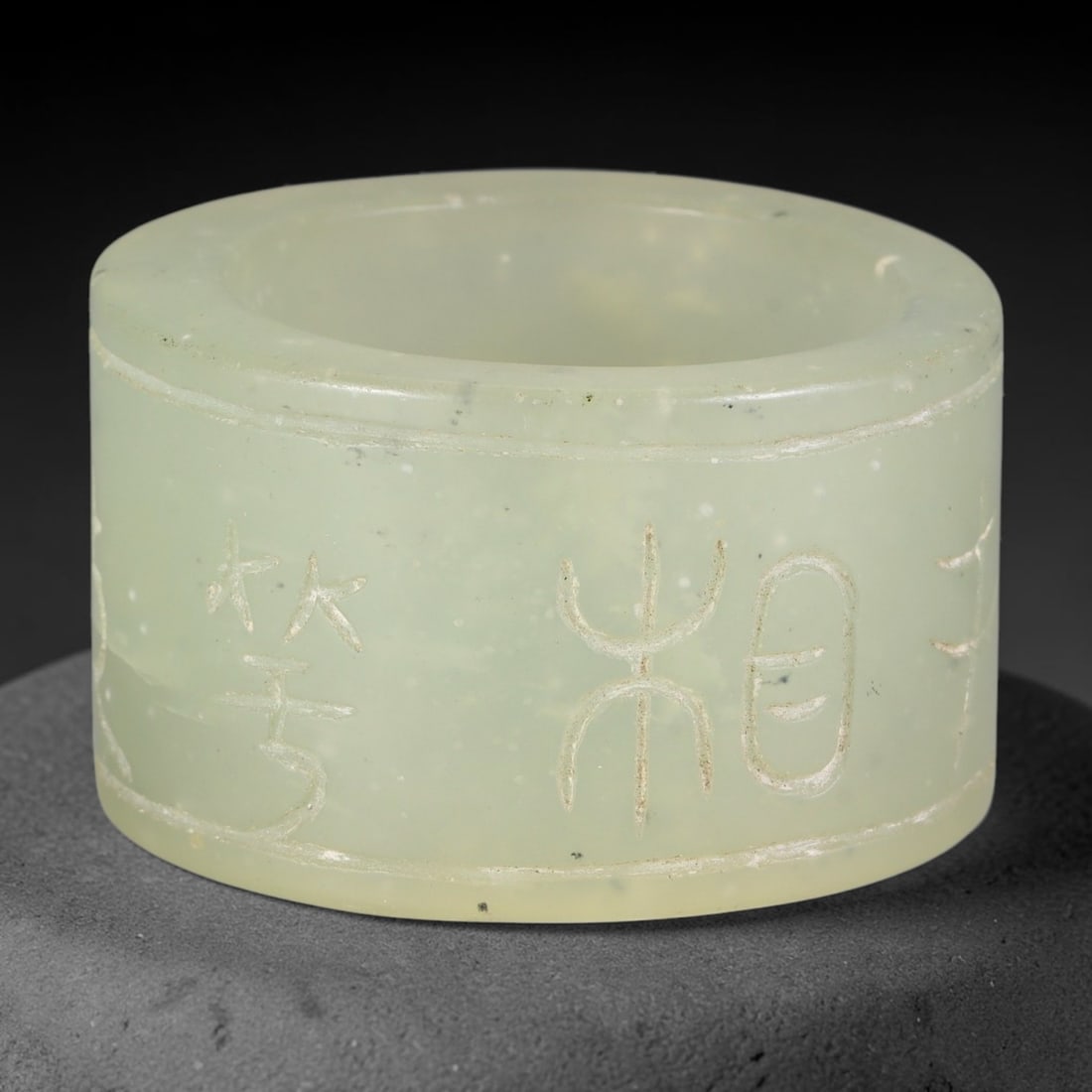 Chinese Nephrite Jade Cylinder - Incised Script Decorative Form, 11AE: Crafted from pale celadon nephrite jade scattered with fine dark mineral speckles across the stone matrix, this hollow cylindrical stone form bears delicately hand-incised archaic Chinese script chara