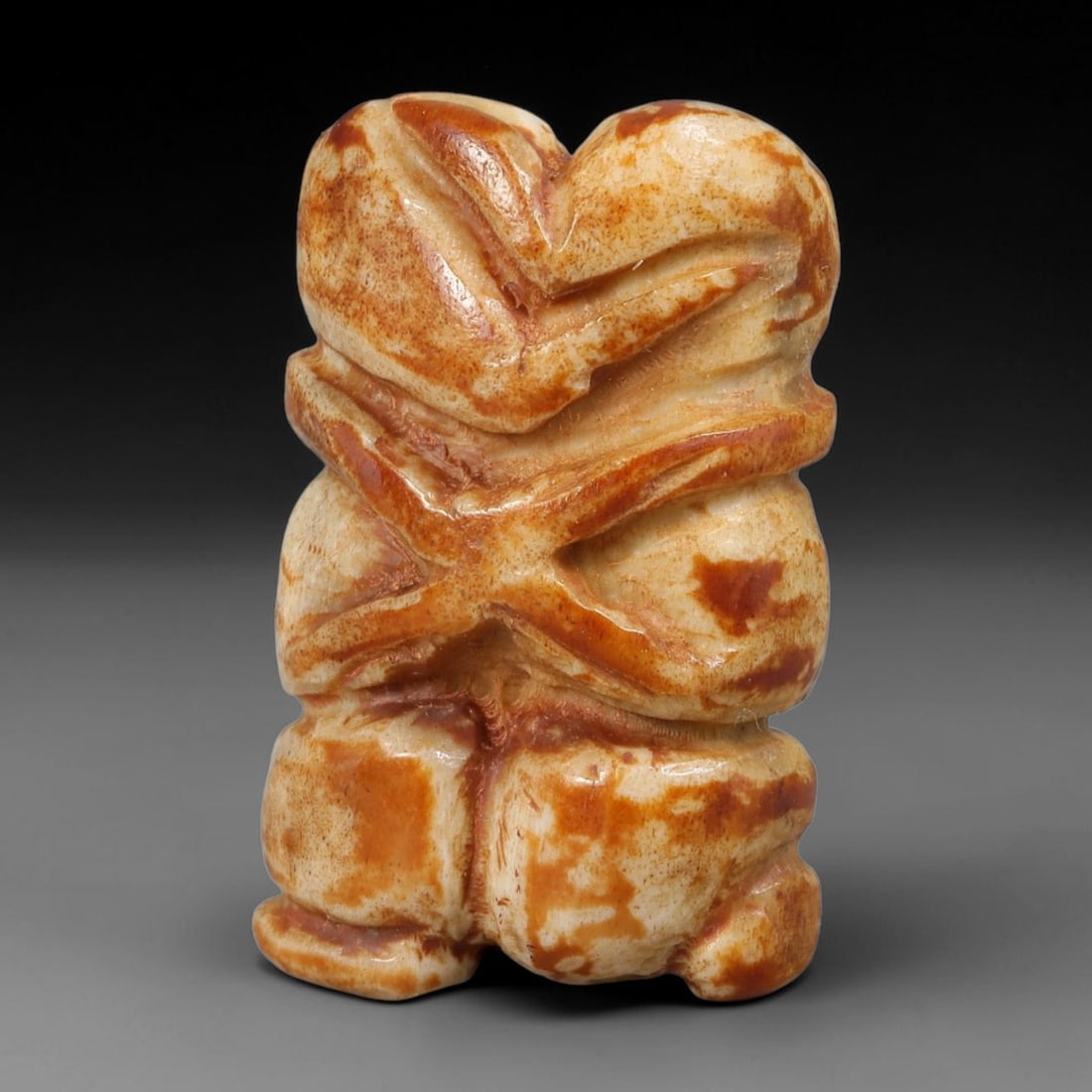 Ancient Primitive Carved Bone Embracing Twin Human Figurine Amulet, 70AB: Miniature hand-carved pale bone talisman depicting two intertwined human figures locked in an embracing pose, a symbol of unity, companionship and protective bonding. Natural amber-brown aged patina m