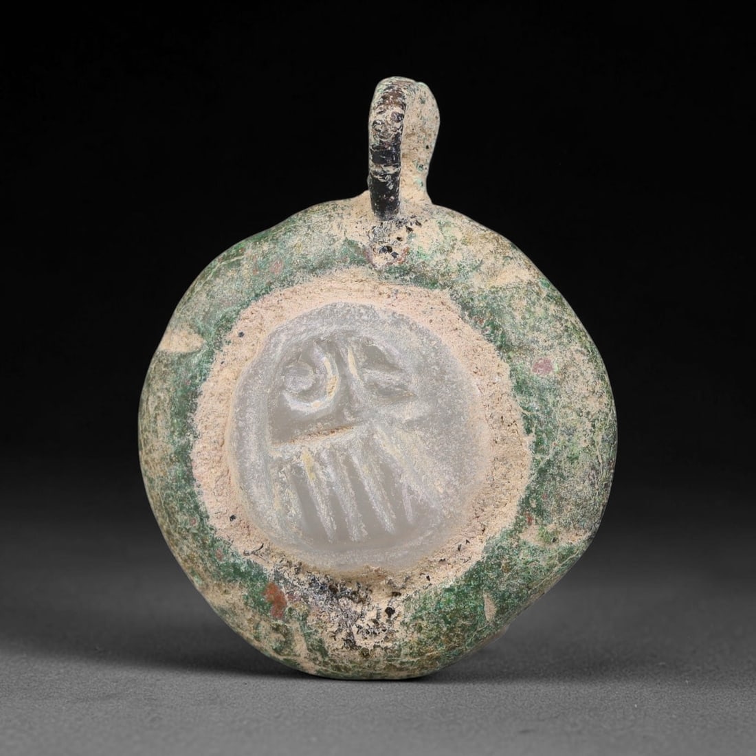 Ancient Medieval Byzantine Bronze Pendant With Stone Cameo (500-1200 CE), 18EG: This antique circular bronze pendant originates from medieval Byzantine cultural tradition, set with an inset carved stone cameo and made to serve as a wearable protective personal amulet. The bronze 