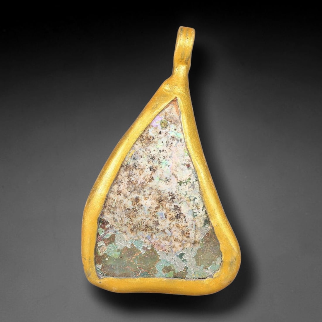 Ancient Roman Glass Slag in Modern Gilt-Edge Pendant, 63FY: This contemporary pendant is crafted from ancient Roman glass slag, featuring a fragmented, iridescent glass surface with weathered patina. The irregular form is bordered by a subtle gilt frame, added