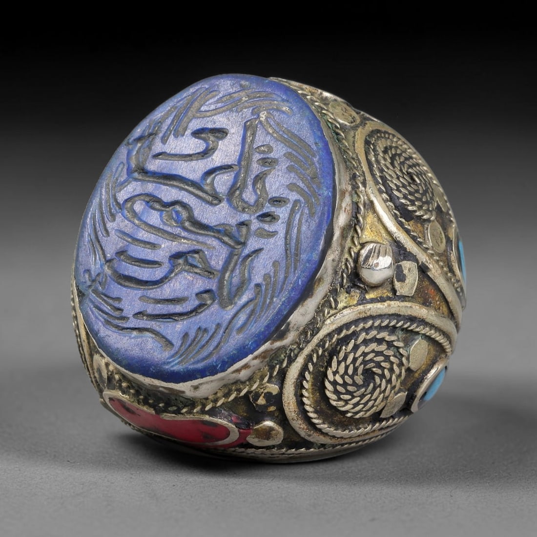 Vintage Islamic Handcrafted Silver Plated Calligraphic Talisman Statement Ring, 12BX: This vintage hand-wrought Islamic statement ring features a central engraved panel bearing traditional calligraphic detailing, set within an ornate silver-plated metal band. The mounting is enriched w