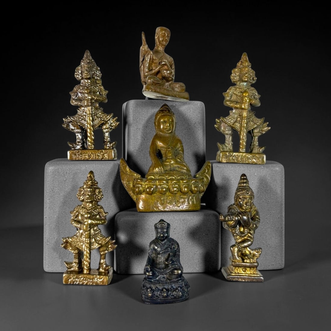 A Lot of 7 Vintage Southeast Asian Brass and Bronze Figurines, 50AA: Comprising seven small cast metal pieces ranging from 3 to 4.5 cm in height. The collection features a variety of devotional and guardian imagery, including seated Buddha and monk figures, multi-heade