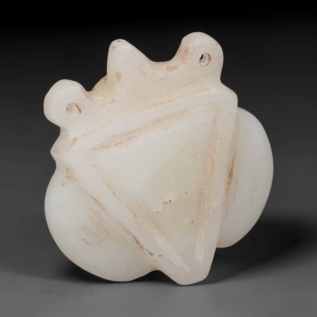Ancient Bactrian Marble Abstract Zoomorphic Mask Amulet (c.200-200 BCE), 59EQ: Hand-carved from pale creamy white marble originating within ancient Bactria, Central Asia. This stylised mask-shaped pendant features twin suspension perforations set at the upper protrusions, design