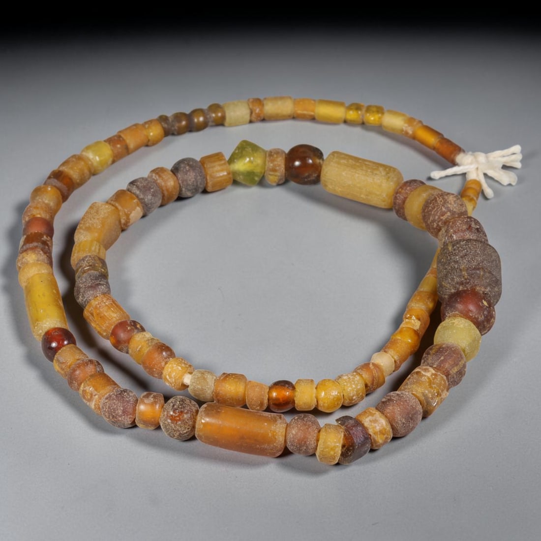 Ancient Egyptian AmberTone Glass Bead Strand, 40EH: Authentic ancient Egyptian glass bead strand featuring beads ranging 3mm10mm. Exhibits natural surface weathering and patina developed over time. Strung asfound, ideal for collector display, historica
