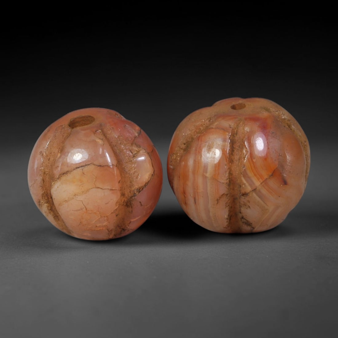 Ancient Medieval Khmer Angkor Culture Carved Carnelian Melon Bead Pair (802-1431 CE), 44AE: This matched pair of antique hand-carved melon form carnelian beads originates from Khmer Angkor Culture, the medieval Southeast Asian civilization renowned for crafting ritual chalcedony adornments f