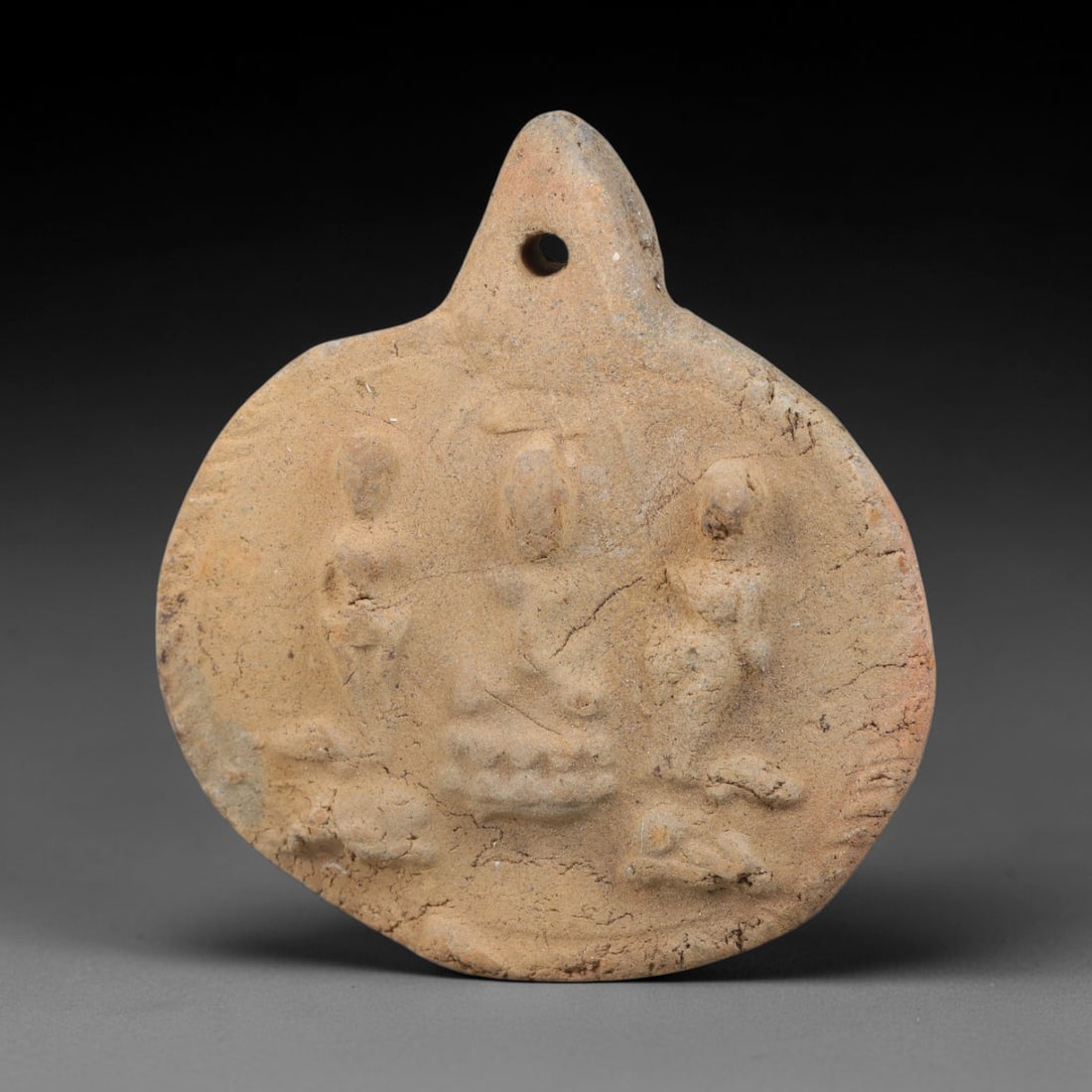 Ancient Gandhara Terracotta Buddhist Plaque (100 BCE-400 CE), 40EK: This ancient terracotta pendant plaque originates from Gandhara, a major centre of early Buddhist art along the Silk Road, shaped as a wearable devotional amulet with an integral suspension hole. The 