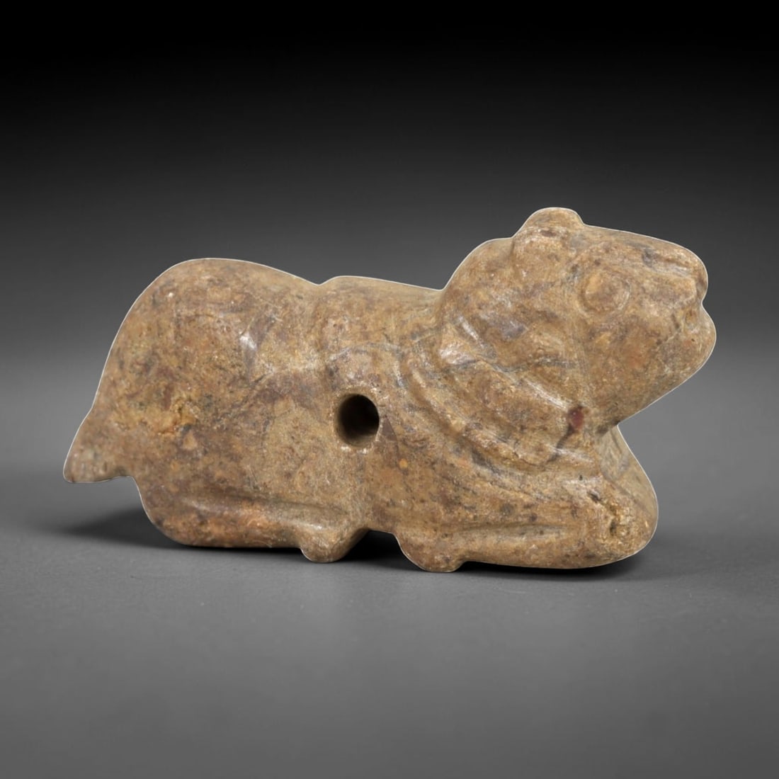 Ancient Stone Zoomorphic Amulet - Near Eastern Animal Figure, 55AM: This amulet is carved from speckled stone, depicting a stylized quadrupedal animal in a crouched, forward-leaning posture, with subtle incised lines defining the neck and facial features. The piece re