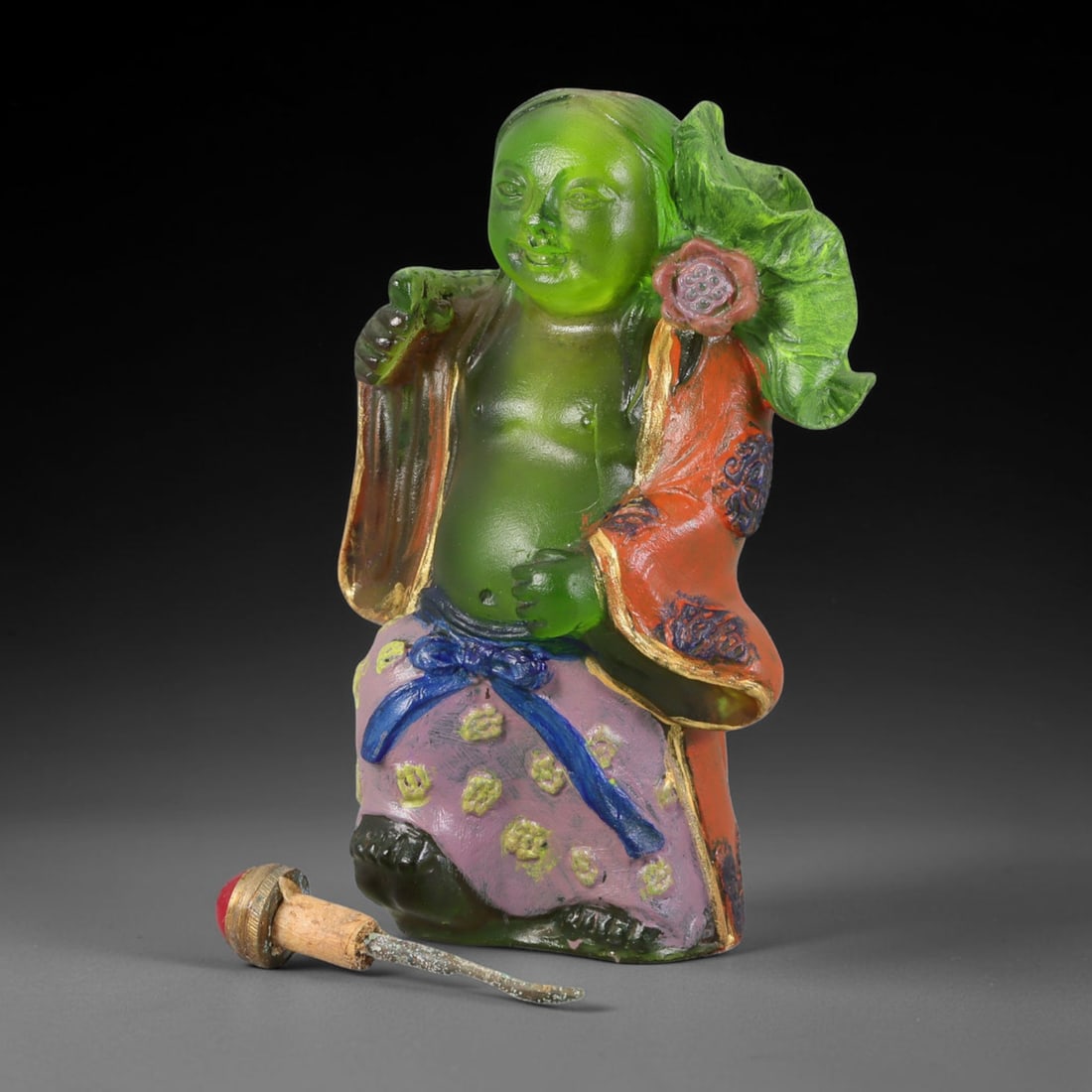 Vintage Chinese Liuli Glass Snuff Bottle - He-He Immortal Figure, 47AS: This snuff bottle is moulded from translucent green liuli glass, shaped as a He-He immortal holding a lotus leaf and flower. The open robe features gilded trim with painted dark floral patterns, while