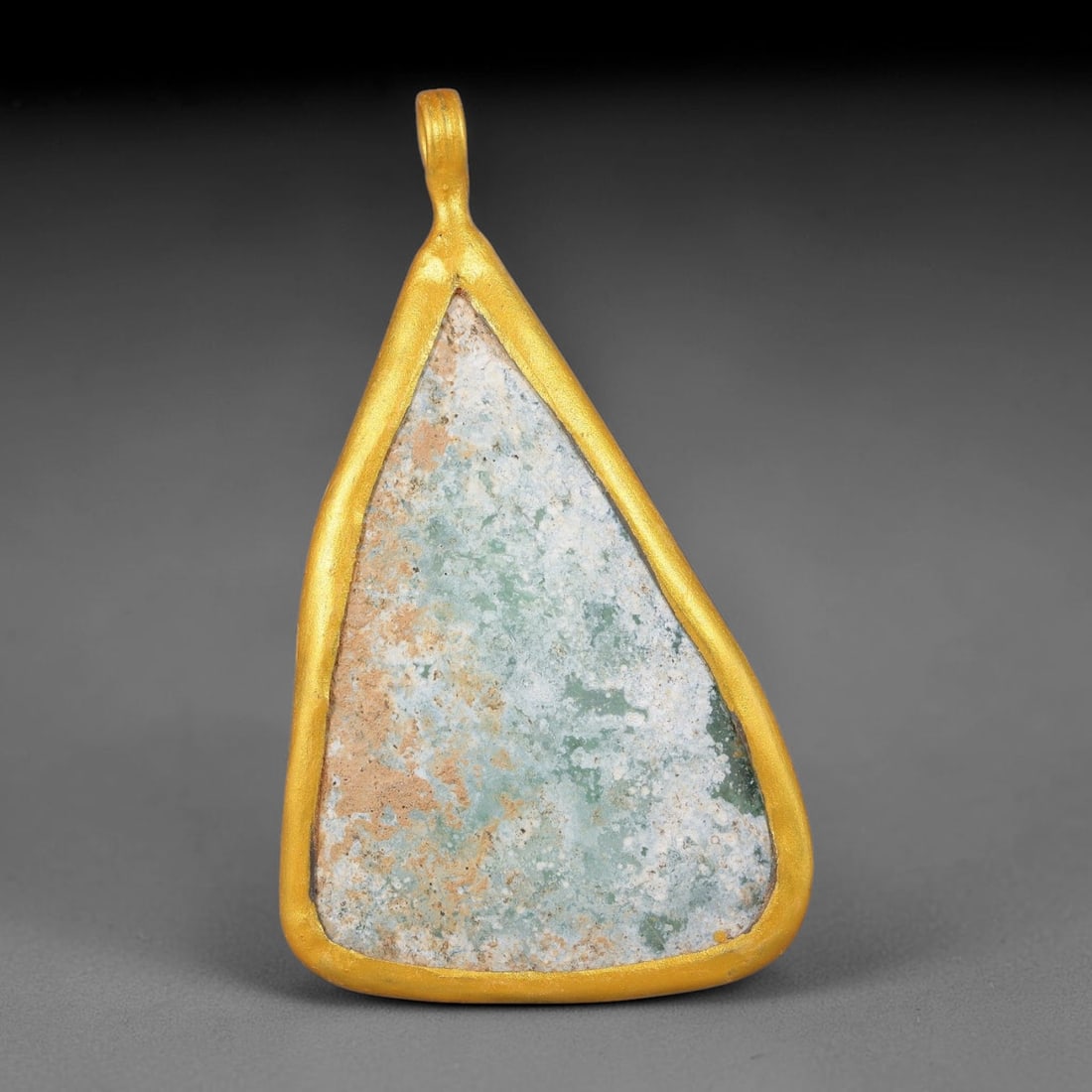 Ancient Roman Glass Slag in Modern Gilt-Edge Pendant, 74FY: This contemporary pendant is crafted from ancient Roman glass slag, featuring a fragmented, iridescent glass surface with weathered patina. The irregular form is bordered by a subtle gilt frame, added