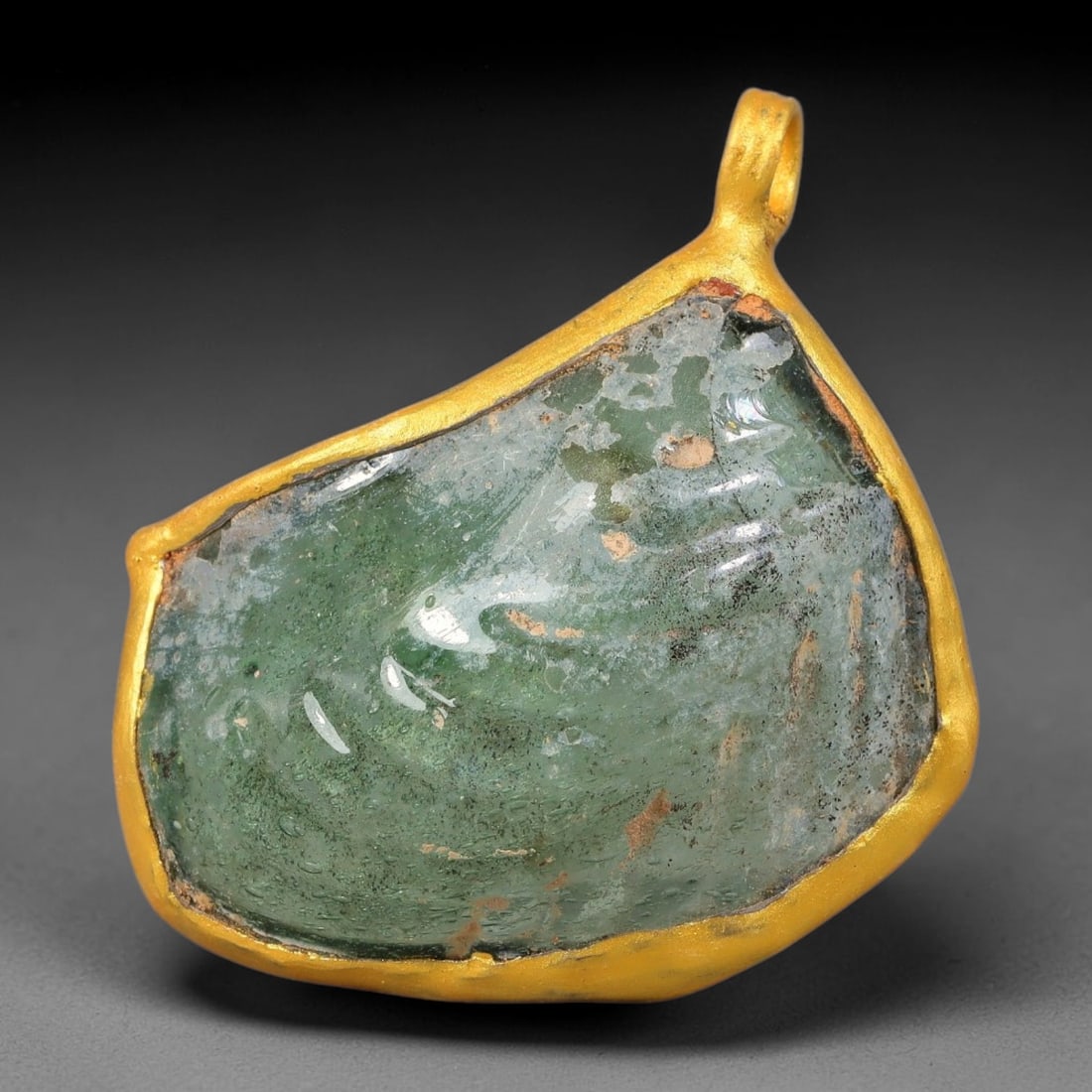 Ancient Roman Glass Slag in Modern Gilt-Edge Pendant, 71FY: This contemporary pendant is crafted from ancient Roman glass slag, featuring a fragmented, iridescent glass surface with weathered patina. The irregular form is bordered by a subtle gilt frame, added