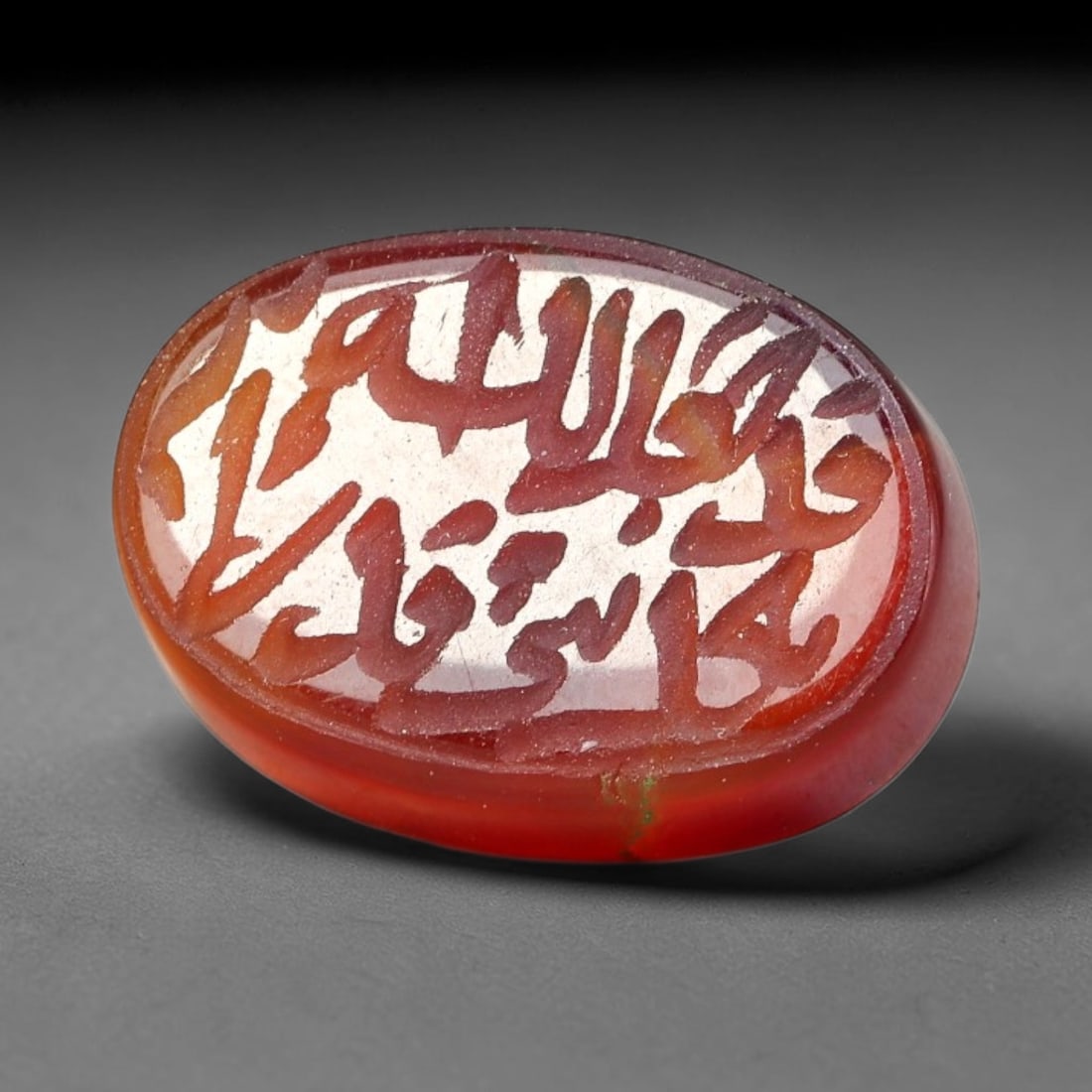 Ancient Medieval Mughal Islamic Carnelian Agate Calligraphic Script Talisman 1526-1857 CE, 59ES: Polished rich-toned carnelian agate cabochon, finely engraved with divided panels of Islamic calligraphic intaglio inscriptions. Deep crisp engraving features segmenting incised lines organizing the s