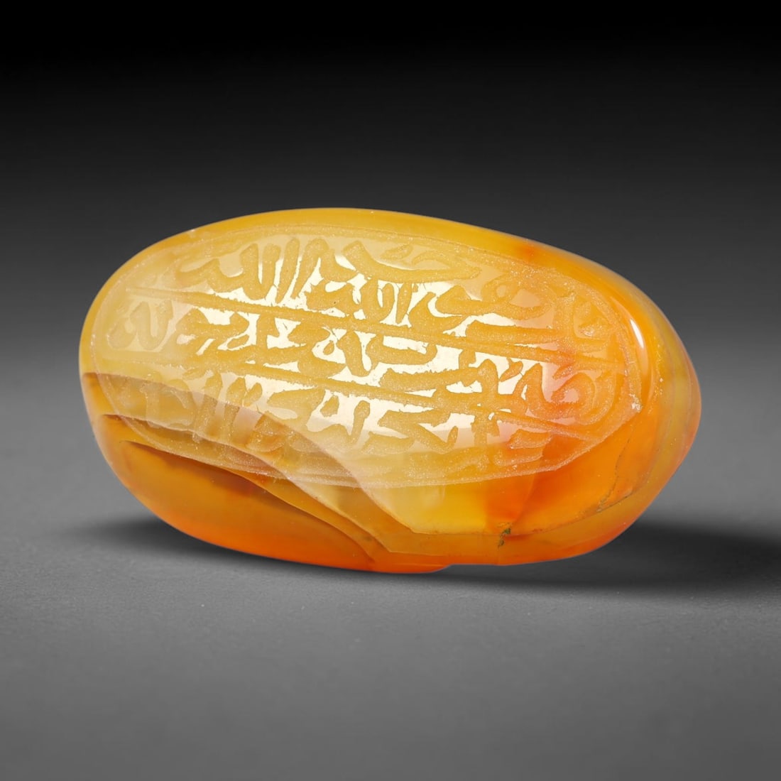 Ancient Medieval Mughal Islamic Carnelian Agate Calligraphic Script Talisman 1526-1857 CE, 27ES: Polished rich-toned carnelian agate cabochon, finely engraved with divided panels of Islamic calligraphic intaglio inscriptions. Deep crisp engraving features segmenting incised lines organizing the s