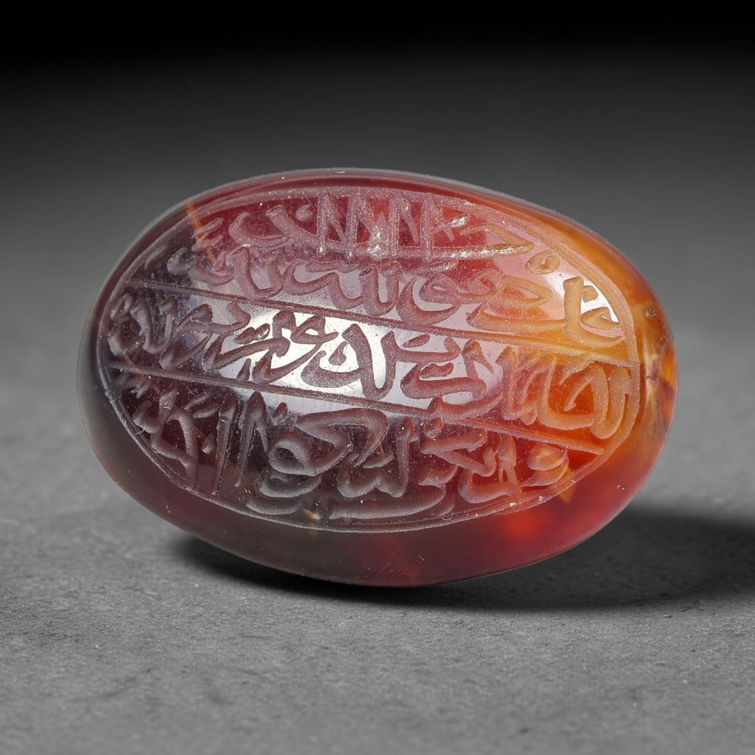 Ancient Medieval Mughal Islamic Carnelian Agate Calligraphic Script Talisman 1526-1857 CE, 4ET: Polished rich-toned carnelian agate cabochon, finely engraved with divided panels of Islamic calligraphic intaglio inscriptions. Deep crisp engraving features segmenting incised lines organizing the s