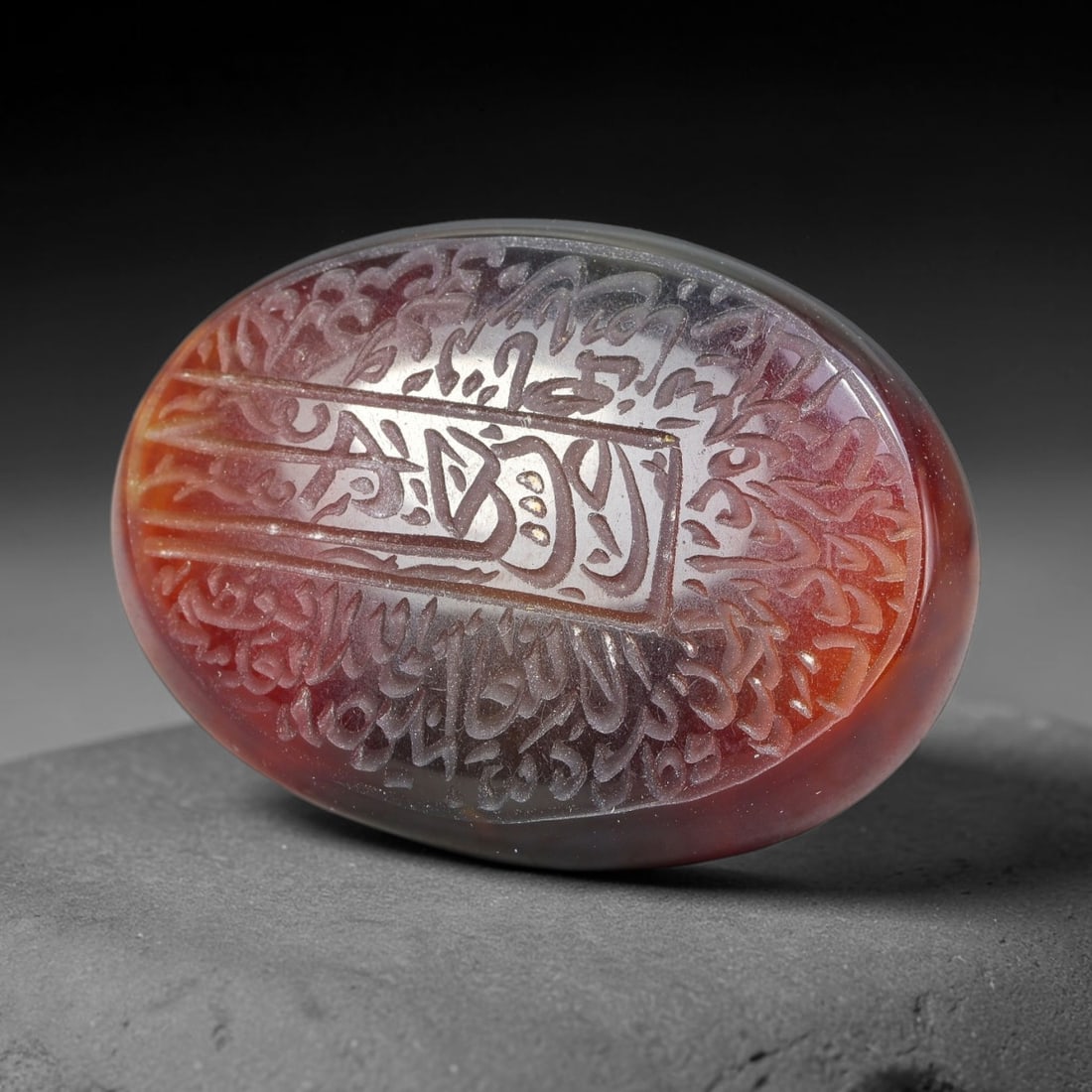 Ancient Medieval Mughal Islamic Carnelian Agate Calligraphic Script Talisman 1526-1857 CE, 80ES: Polished rich-toned carnelian agate cabochon, finely engraved with divided panels of Islamic calligraphic intaglio inscriptions. Deep crisp engraving features segmenting incised lines organizing the s