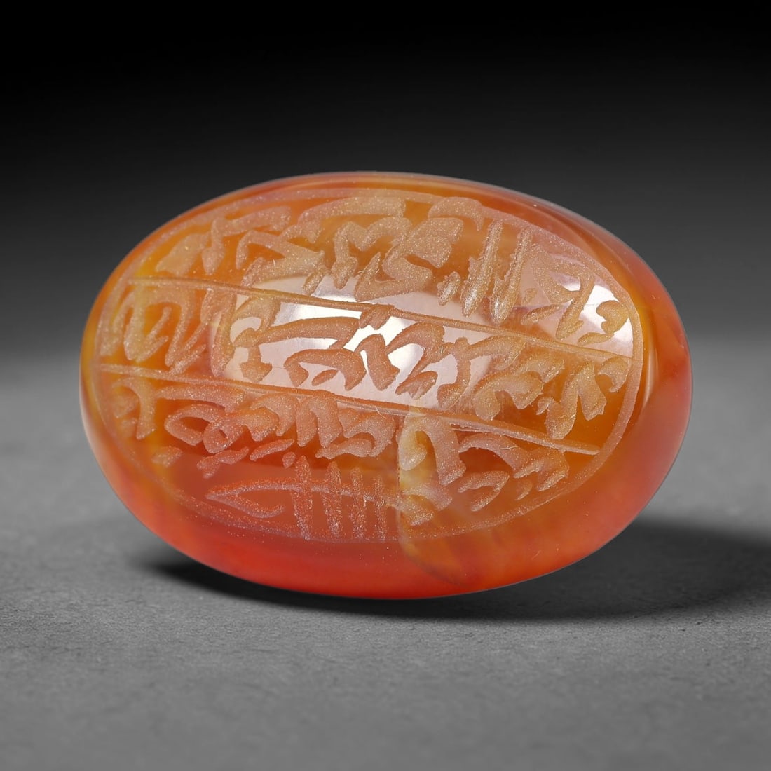 Ancient Medieval Mughal Islamic Carnelian Agate Calligraphic Script Talisman 1526-1857 CE, 3ET: Polished rich-toned carnelian agate cabochon, finely engraved with divided panels of Islamic calligraphic intaglio inscriptions. Deep crisp engraving features segmenting incised lines organizing the s