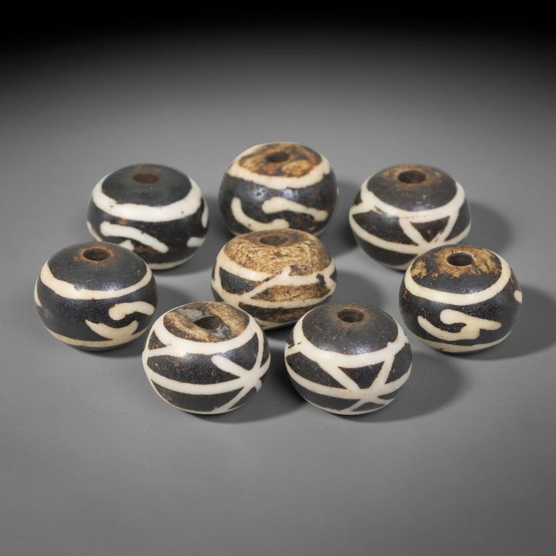Antique Indo-Himalayan Pumtek Wood Round Etched Beads, 7EV: A curated collection of eight antique Indo-Himalayan pumtek wood round beads, each featuring distinct traditional etched tribal symbolic motifs. The beads display rich time-earned patina, natural surf