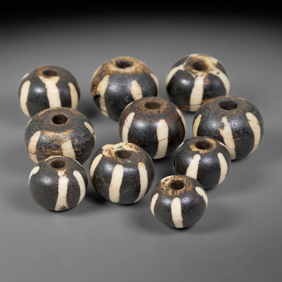 Antique Indo-Himalayan Pumtek Wood Round Striped Etched Beads, 2EV: Fine assembled set of antique Indo-Himalayan pumtek wood round beads decorated with classic vertical etched stripe motifs. The grouping shows natural material variation, deep accumulated patina, and g