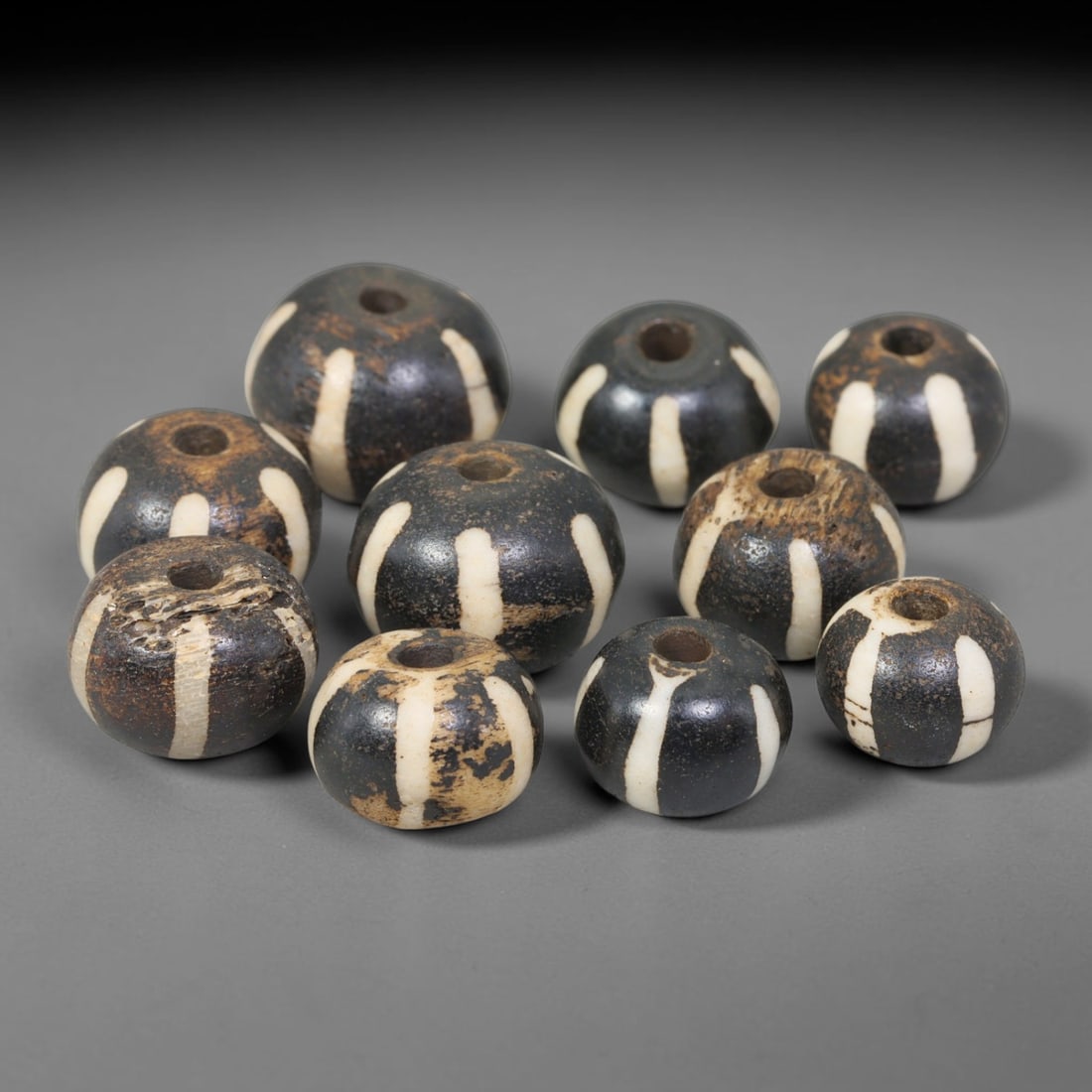 Antique Indo-Himalayan Pumtek Wood Round Striped Etched Beads, 4EV: Fine assembled set of antique Indo-Himalayan pumtek wood round beads decorated with classic vertical etched stripe motifs. The grouping shows natural material variation, deep accumulated patina, and g