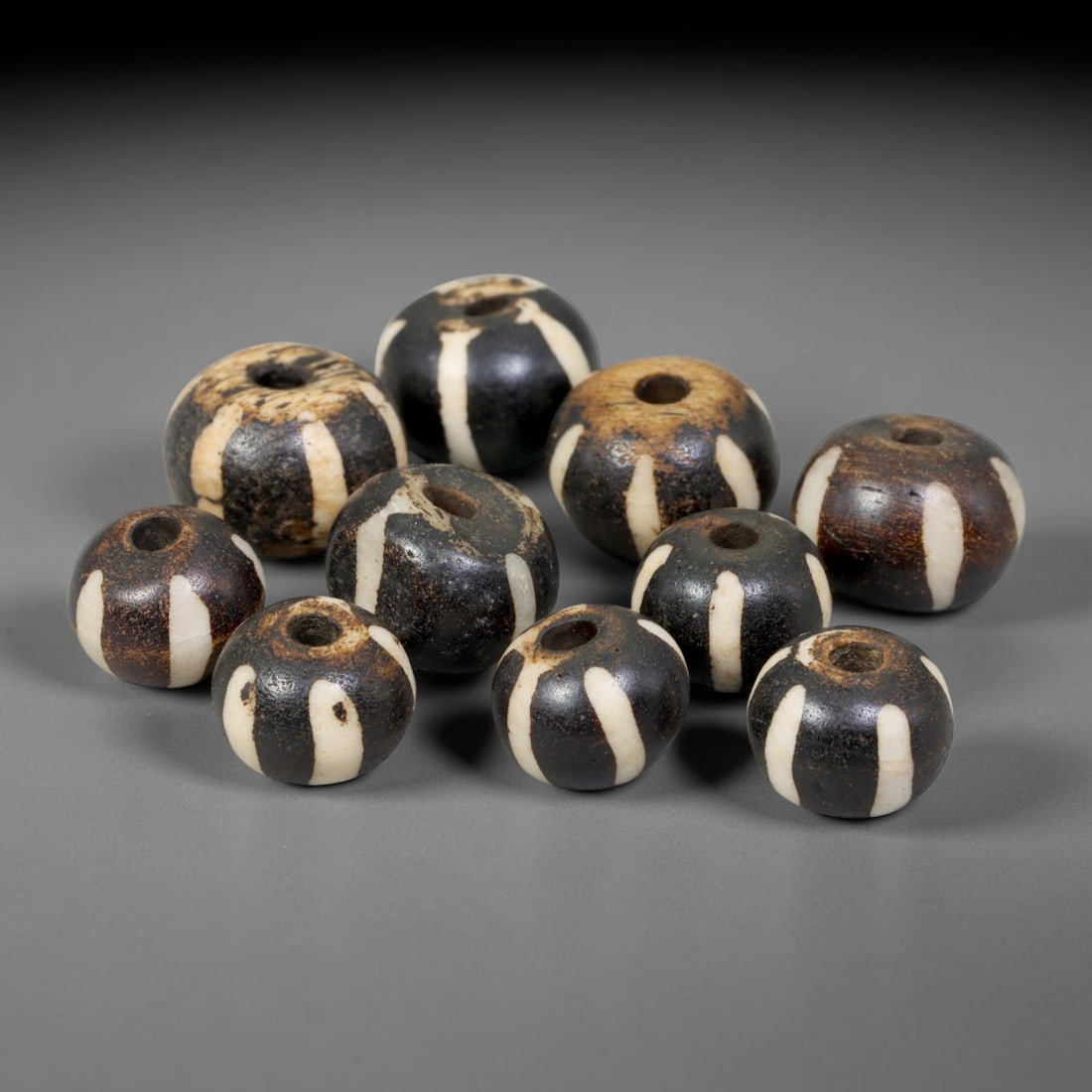 Antique Indo-Himalayan Pumtek Wood Round Striped Etched Beads, 100ET: Fine assembled set of antique Indo-Himalayan pumtek wood round beads decorated with classic vertical etched stripe motifs. The grouping shows natural material variation, deep accumulated patina, and g