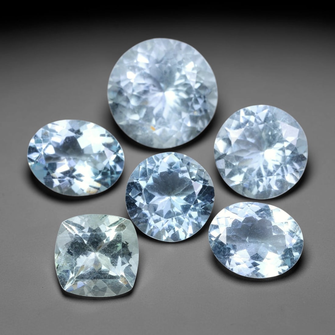 12.98ct Natural Brazilian Sky Blue Aquamarine Loose Gemstone Parcel Lot, 56EV: This lovely parcel of aquamarine displays serene sky-blue cool tones across a varied selection of oval, cushion and emerald faceted cuts. Crisp faceting allows light to travel through each translucent