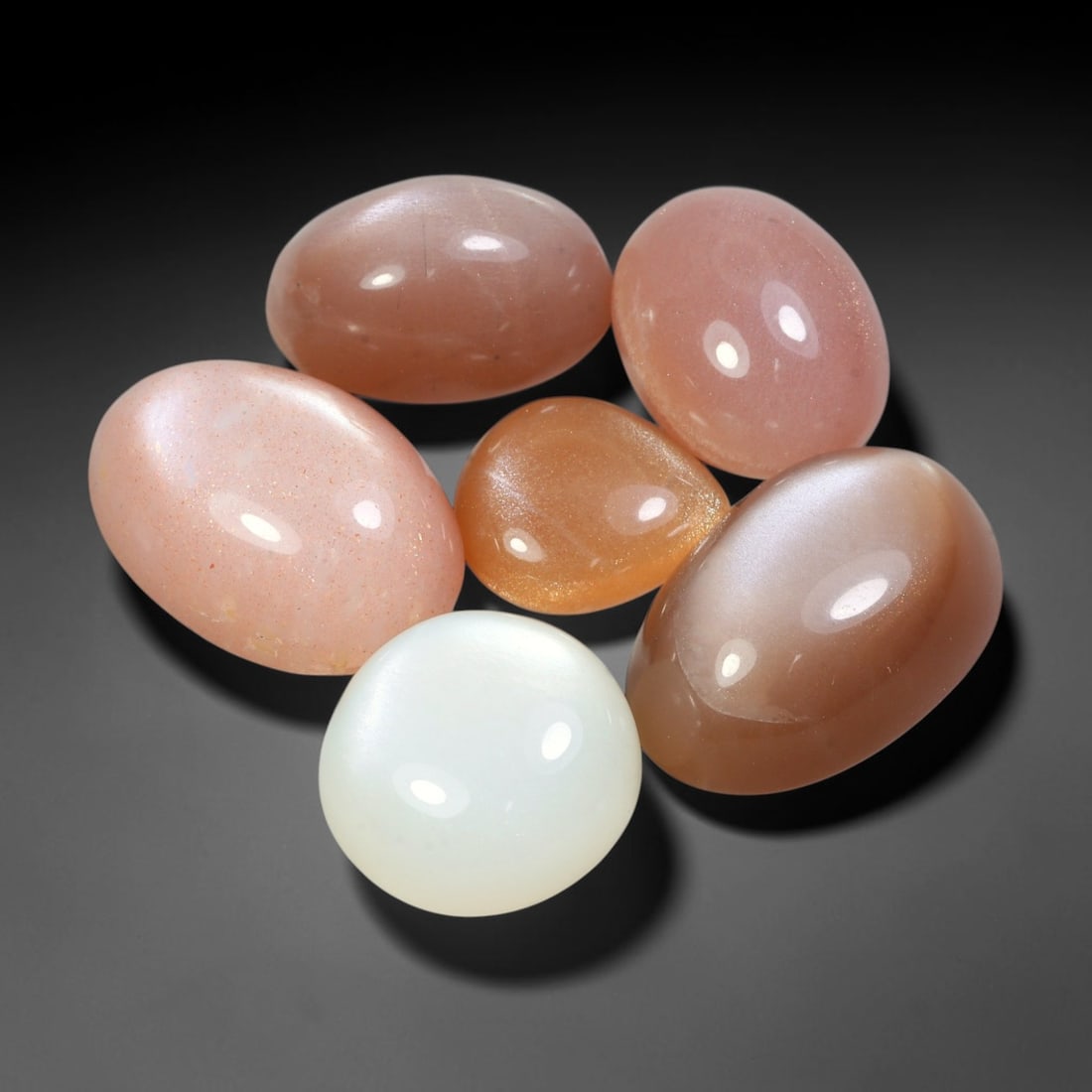 82.02ct Natural Ceylon Moonstone Cabochon Loose Gemstone Parcel Lot, 95EV: This substantial parcel of Ceylon moonstone cabochons showcases soft milky white, warm peach-pink and cool grey-silver tones across smoothly polished oval domed forms. Gentle adularescent sheen drifts
